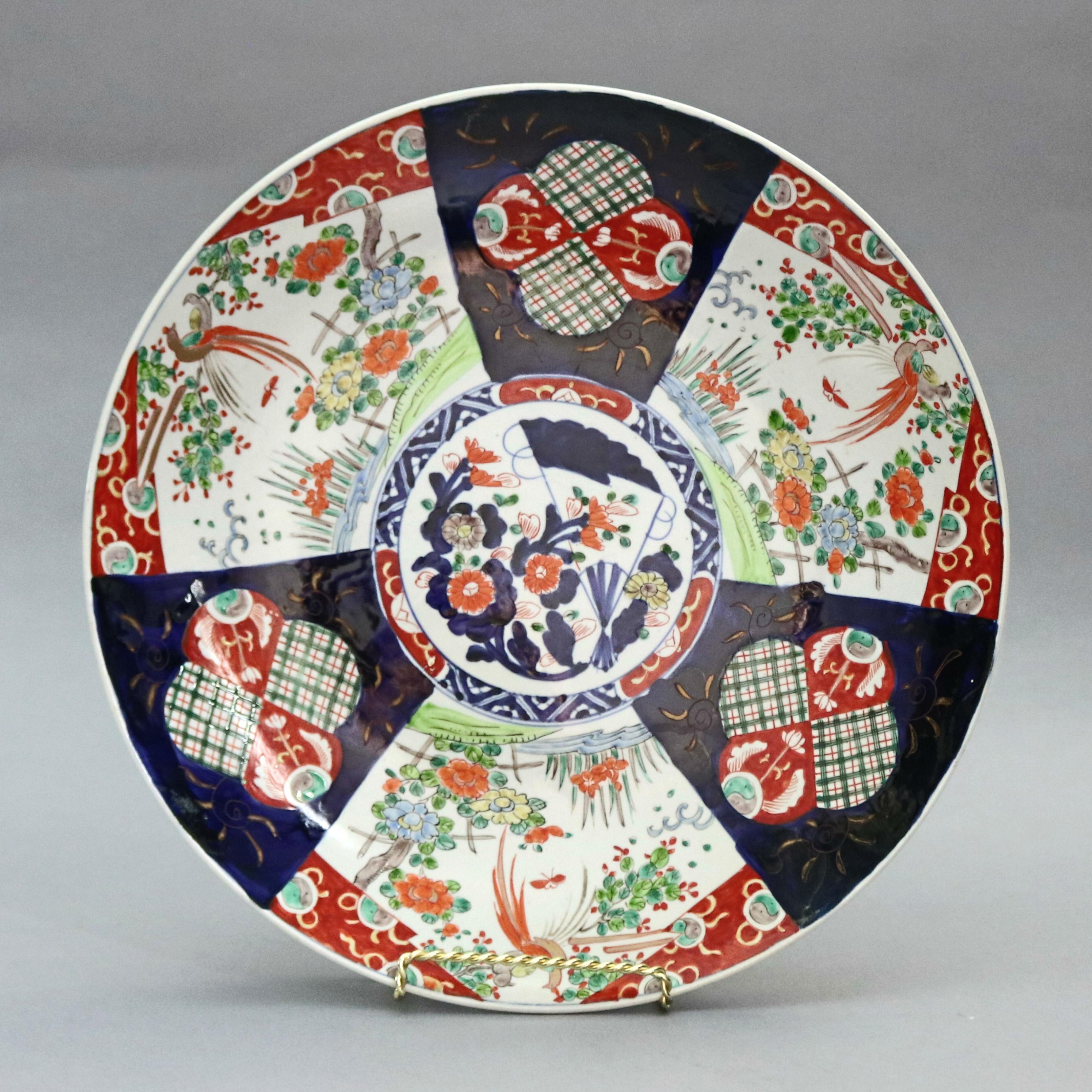 An antique and oversized Japanese Imari charger offers porcelain construction with central medallion having garden scene with fan surrounded by panels having garden elements, en verso blue paint decorated, circa 1900

Measures: 2.5