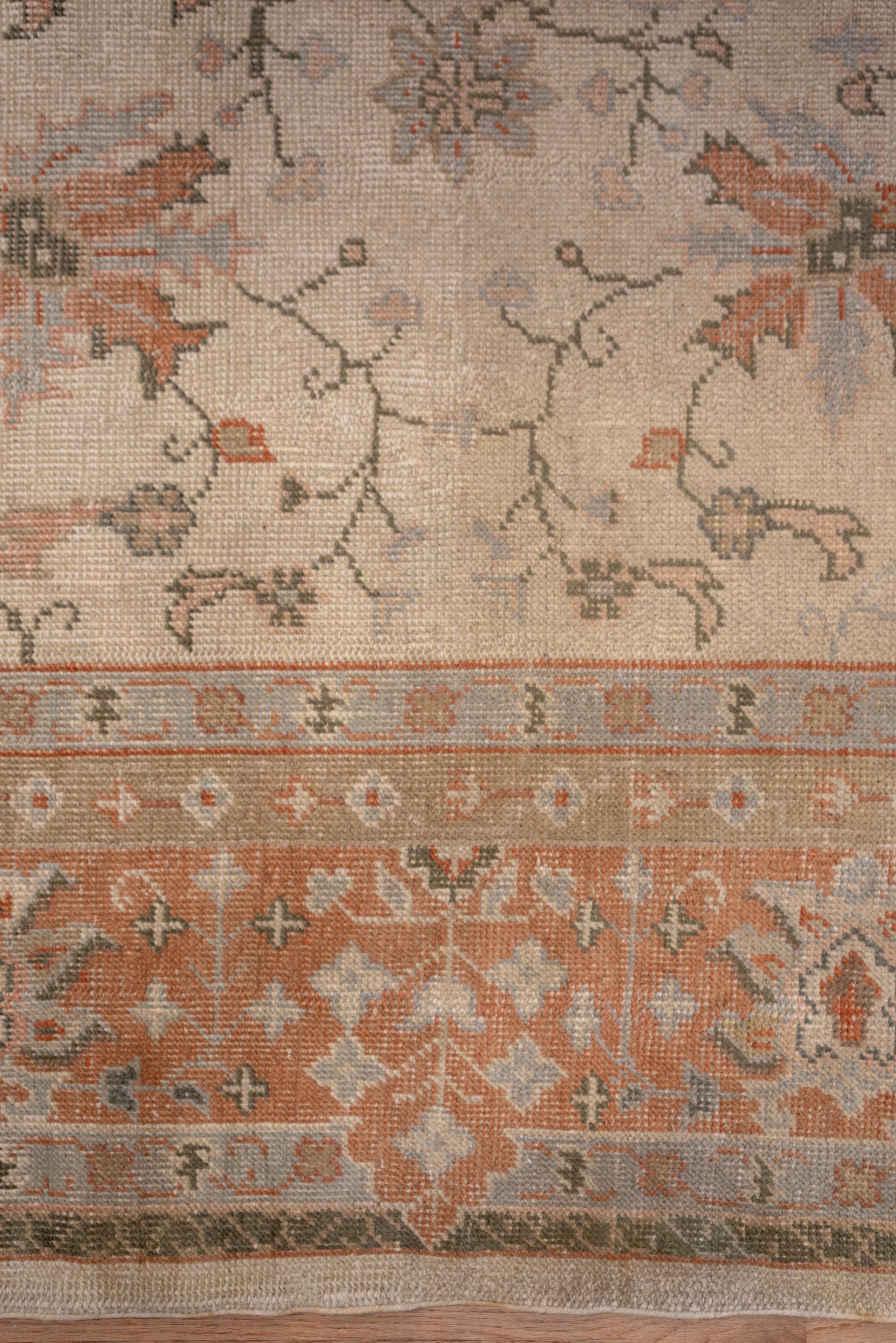 This cotton warp, west Anatolian oversize town carpet with all-over even wear features a light salmon palmette and flower partially broken main border framing the ivory eggshell field with extended pale green corners. The ivory eggshell field is