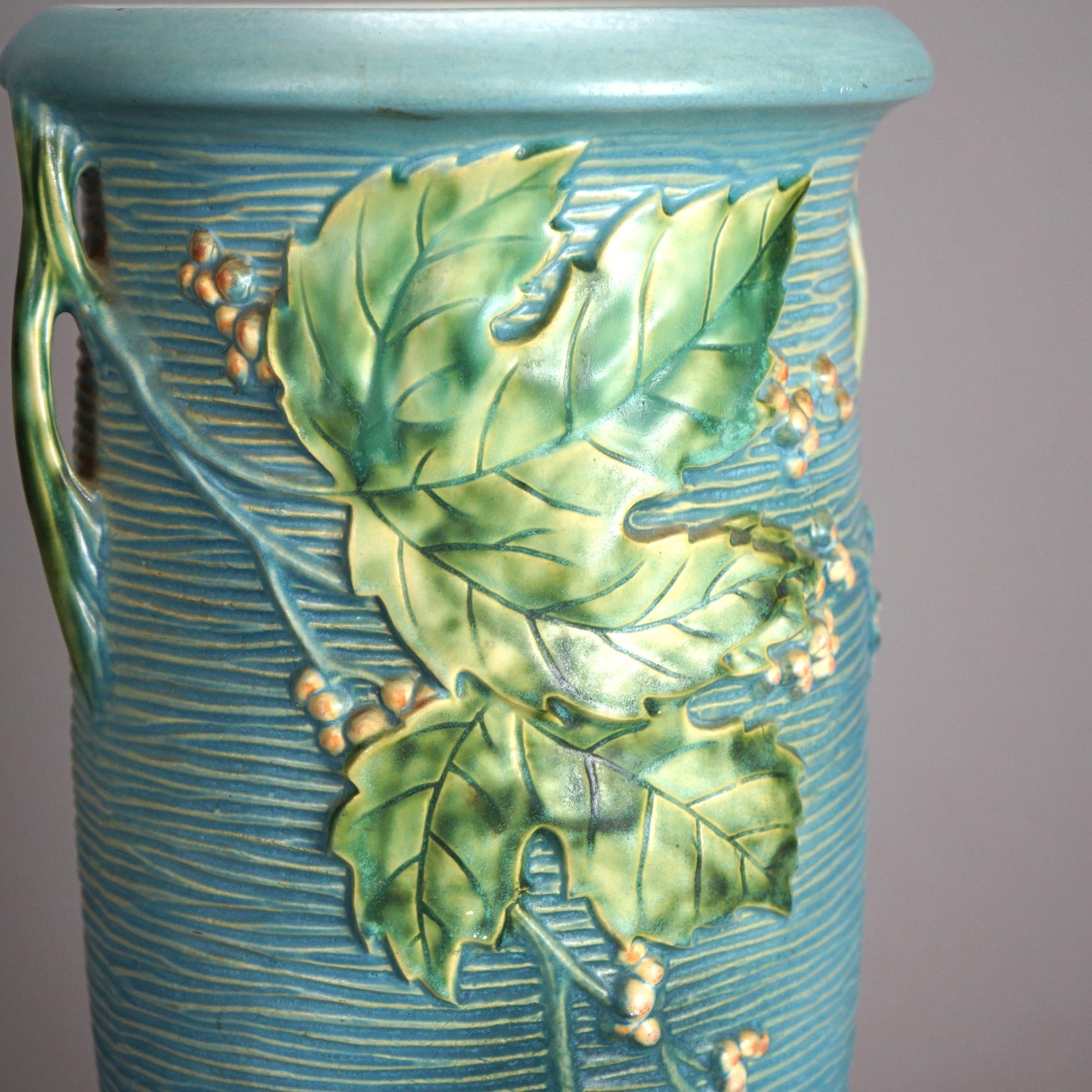 An antique oversized Roseville vase offers art pottery construction with double handles and in the Bushberry pattern; maker mark on base as photographed; c1930

Measures - 20.25