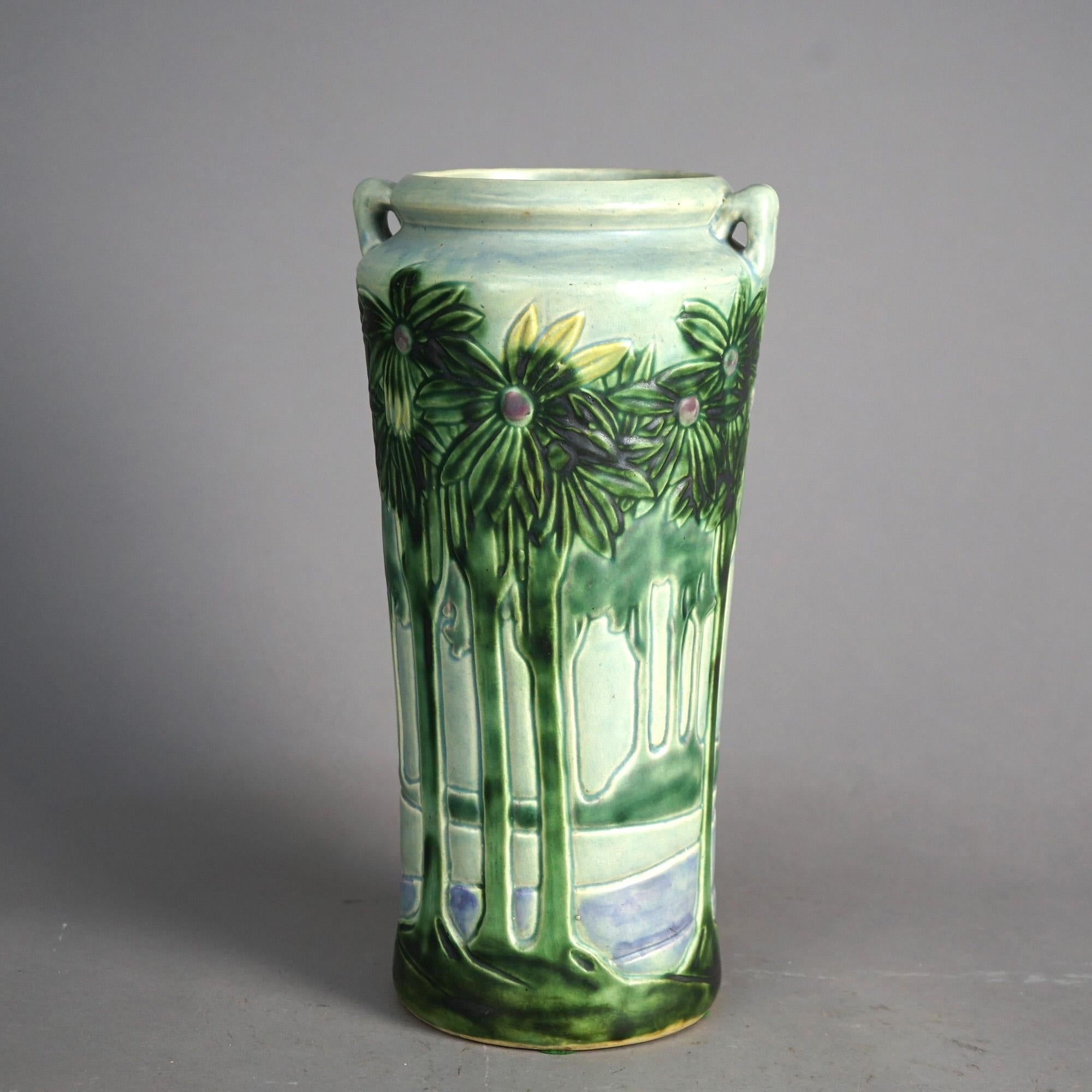 An antique and large vase by Roseville offers art pottery construction in cylindrical form with double handles and having Vista design with trees and water, c1920

Measures - 15