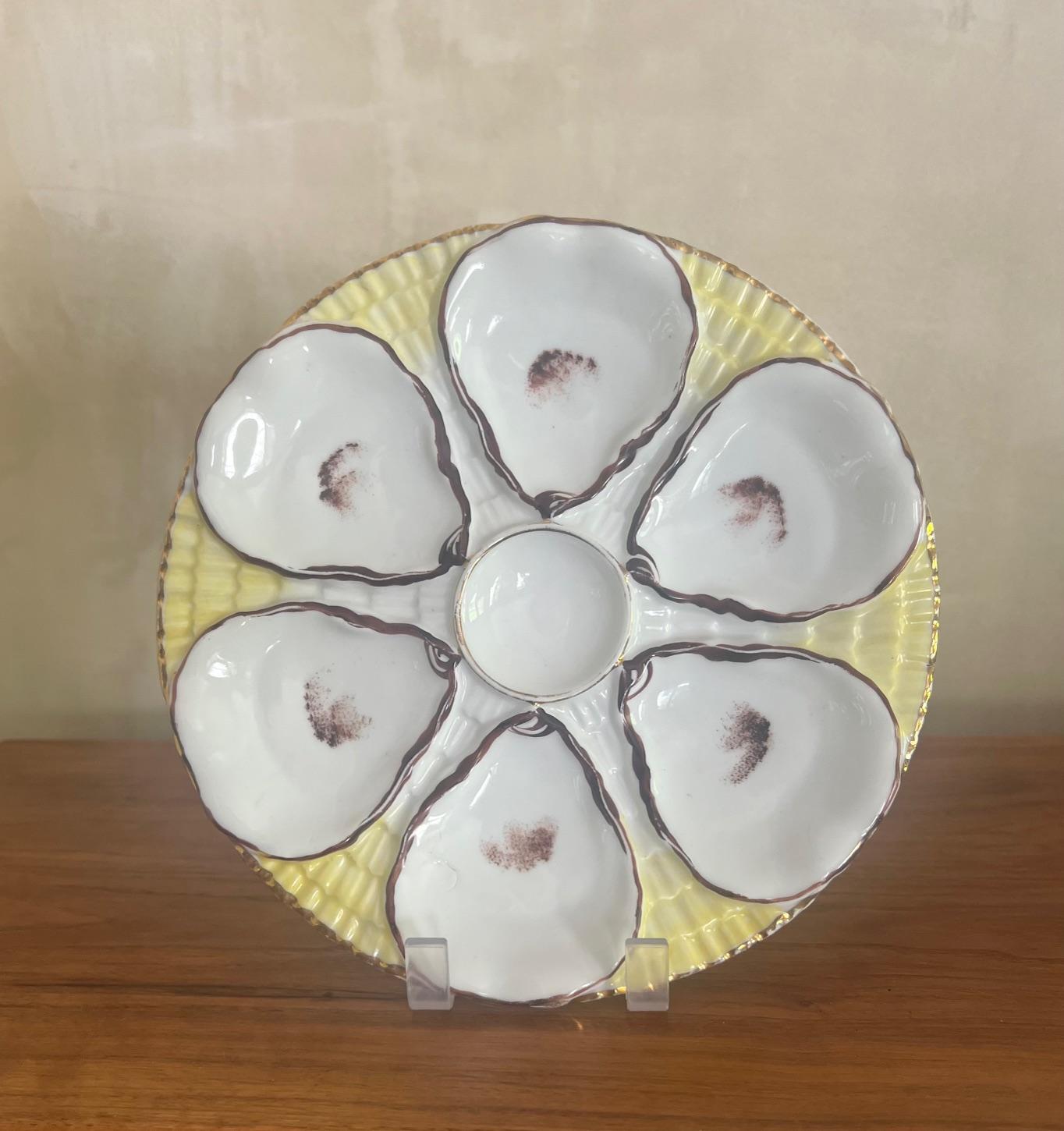 Antique oyster plate made by Carl Tielsch in the late 19th century in Germany.  The plate has six wells for oysters and a center well for lemon wedges. The background is a vivid yellow with a gold rim. Hallmarked on the bottom for Carl Tielsch.