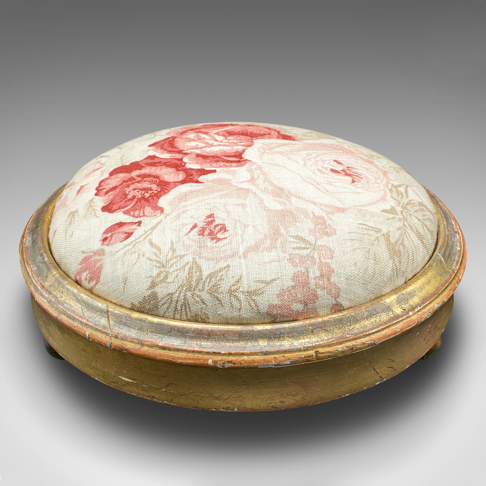 This is an antique padded footstool. An English, giltwood lounge stool, dating to the Regency period, circa 1820.

Delightful foliate interest and appealing colour throughout
Displays a desirable aged patina and in good order
Striking giltwood