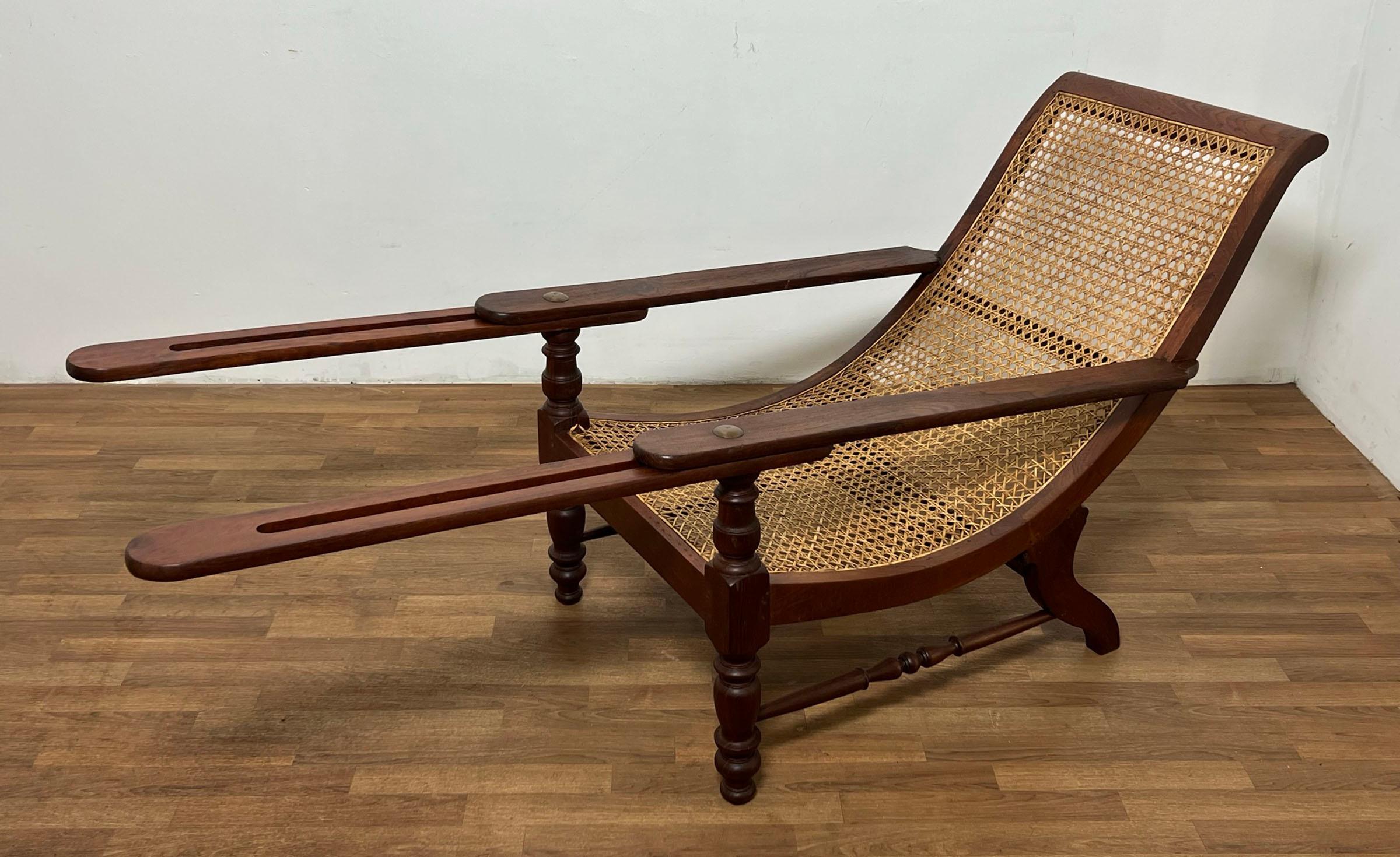An original antique Anglo-Indian long paddle arm plantation lounge chair in solid teak circa late 19th century. Retains its underarm 
extensions for reclining with legs up.  

Depth is 51.5