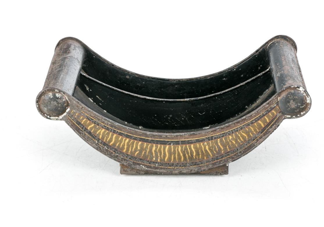 A two compartment cheese wheel with scrolled ends in tole painted black with tan faux bois decoration on the curved sides. The two part base raised on bun feet. Likely English. 

Dimensions: 13 1/2
