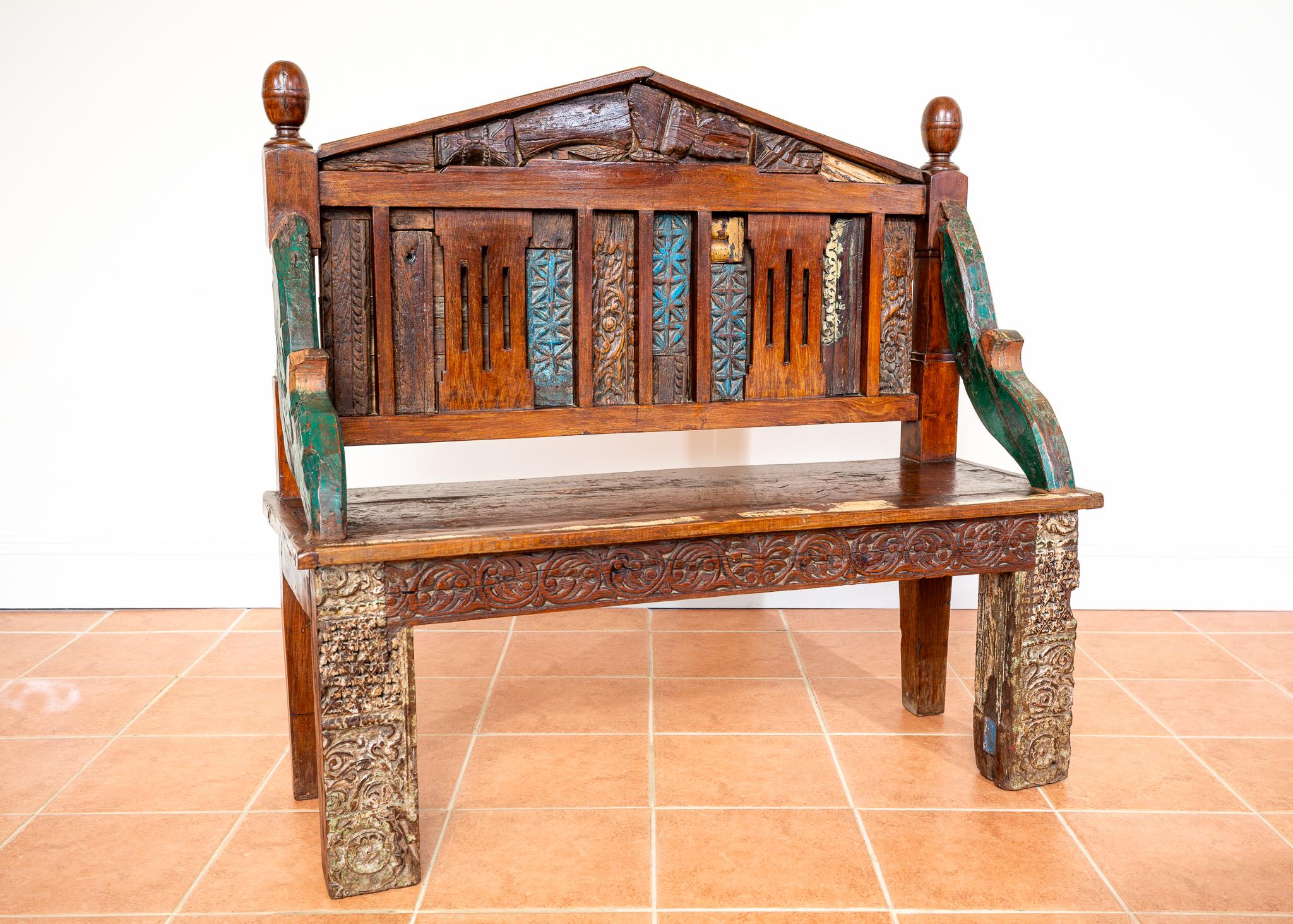 An impressive, eye-catchingly attractive and rare Indian bench in lovely antique condition. Hand-crafted in Rajasthan from wonderfully decorative and colourful pieces of 19th Century Raj era architecture, this colourful, sculptural and very