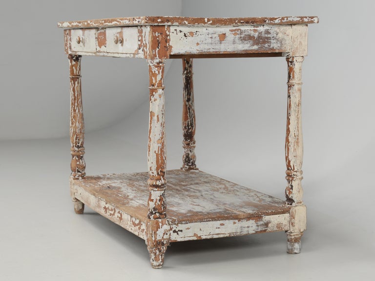 Antique French side table, end table or small writing desk in old crumbly paint. Two convenient drawers and most often these were small writing tables. Probably constructed around 1900 and the paint is old and has seen better days. 
**Please note