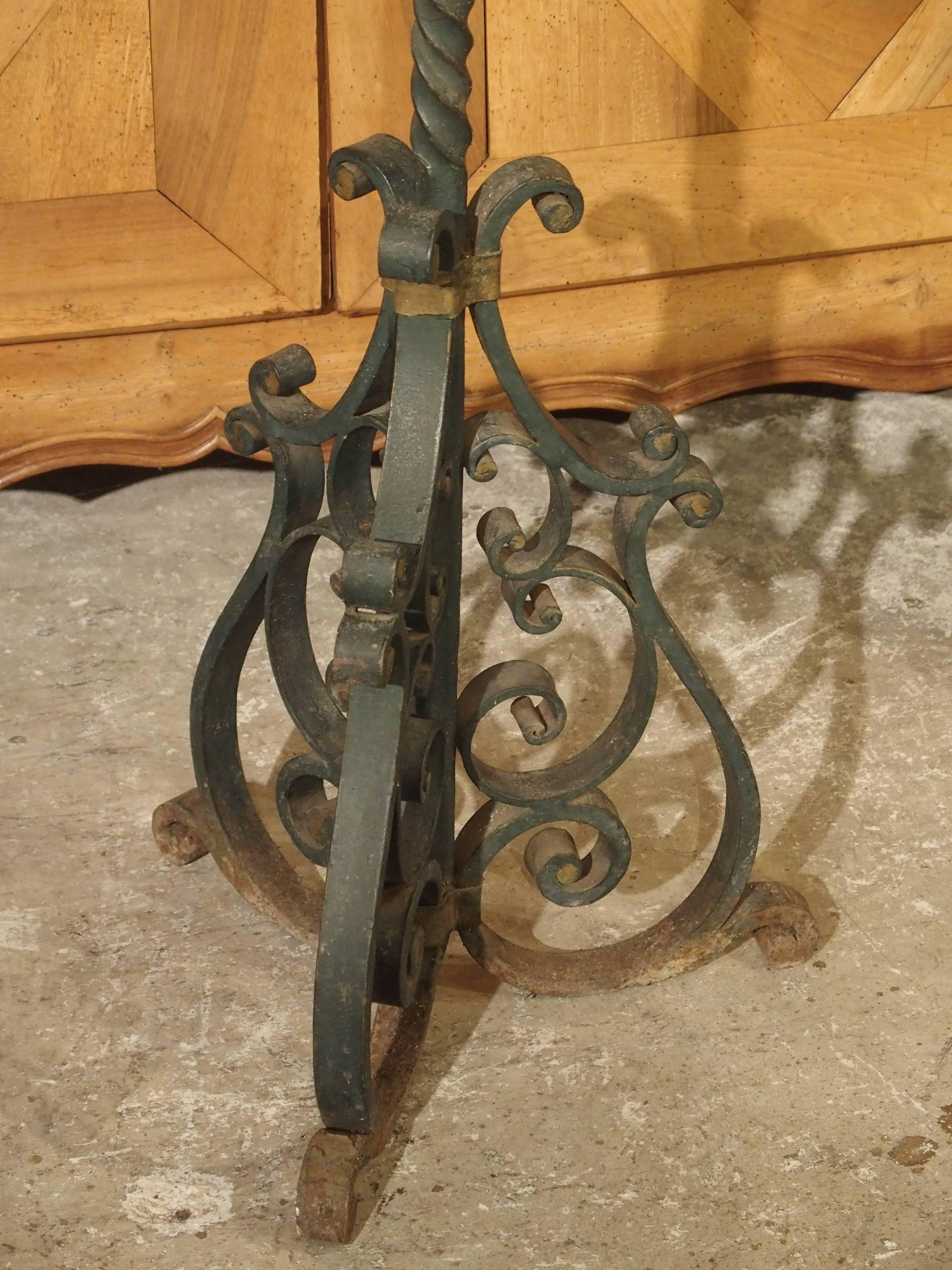 This five light, antique French cast iron torchere has been painted deep green with gold colored bands around the motifs. The motifs are trefoils, C-scrolls, and S-scrolls. There is a turned central stem with a large ball motif at the center ending