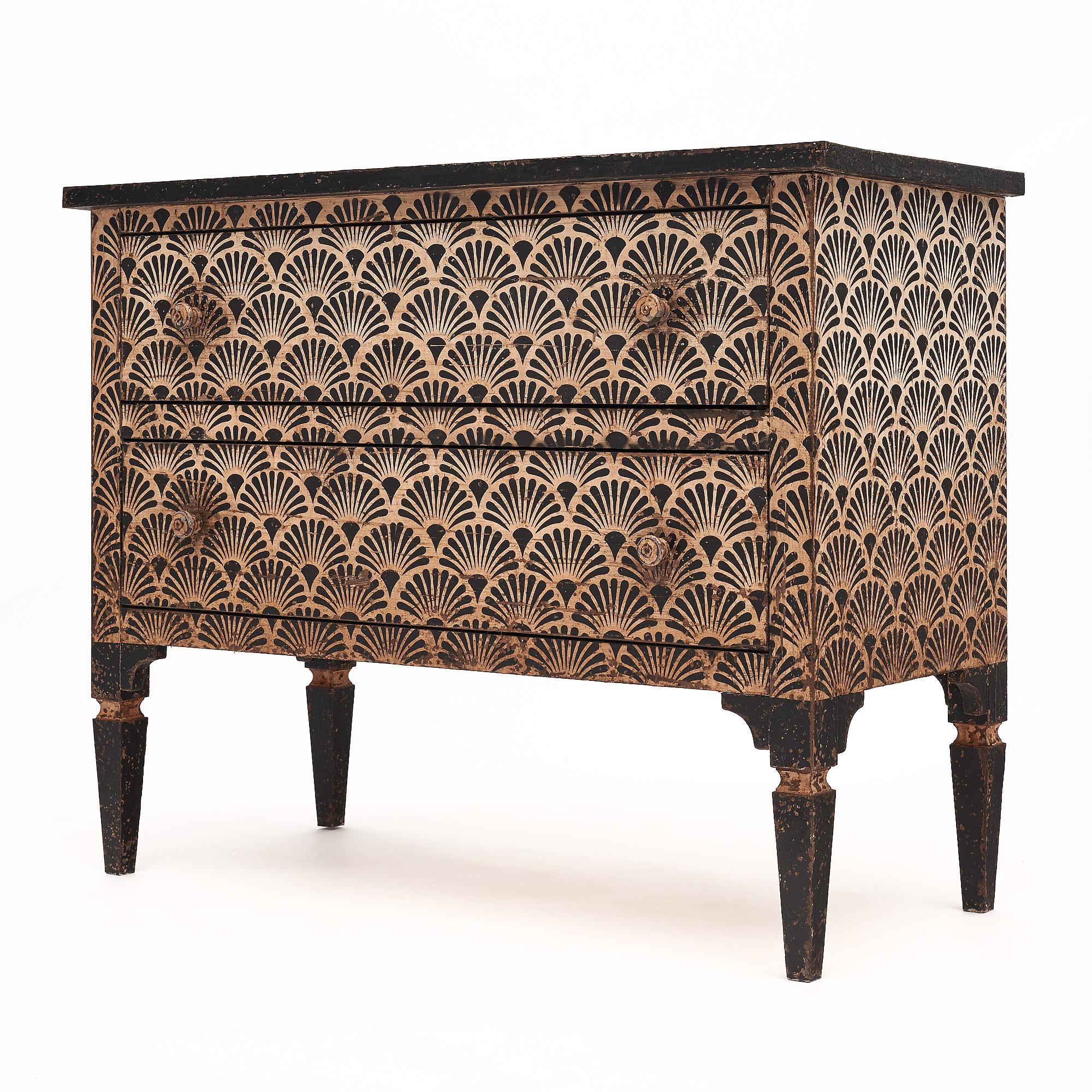 Chest from Italy that features a striking hand-painted design in cream and black tones showcasing a scalloped design. The chest is supported by four tapered legs and has two dovetailed drawers.
