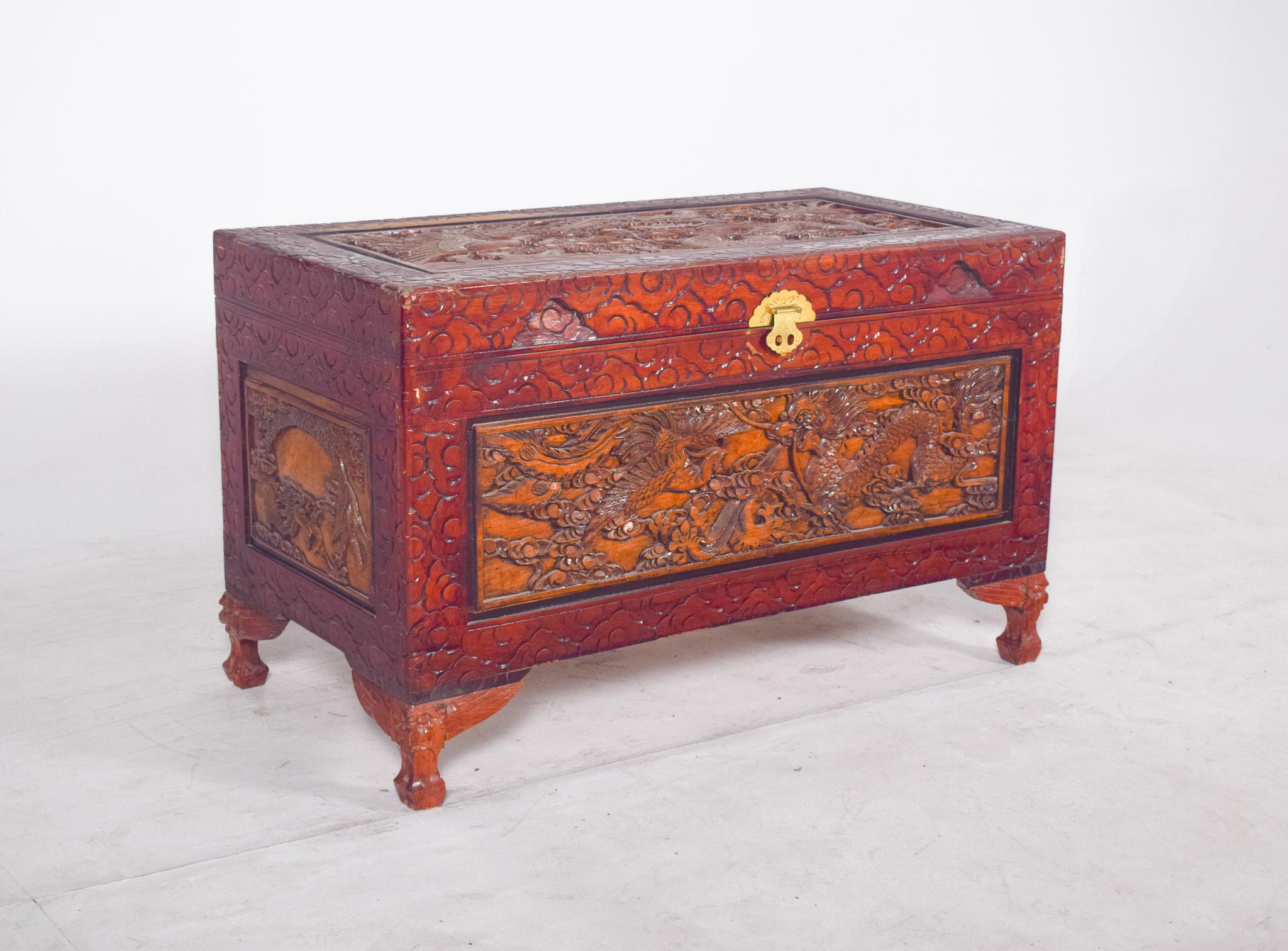Oriental carved chest. The front features a scene of dragons among clouds, a symbol of power and protection in Chinese iconography. The sides are also decorated with details of fauna and flora scenes, all framed by floral patterns all over the