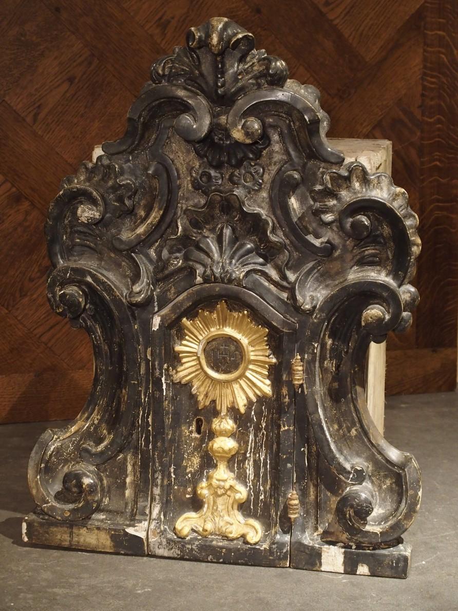 This beautifully carved and very old tabernacle is of Italian origin, and dates the mid-18th century. It’s black painted facade with gold highlights, has a small functioning door, which opens to an interior with original, though partial silk lining.