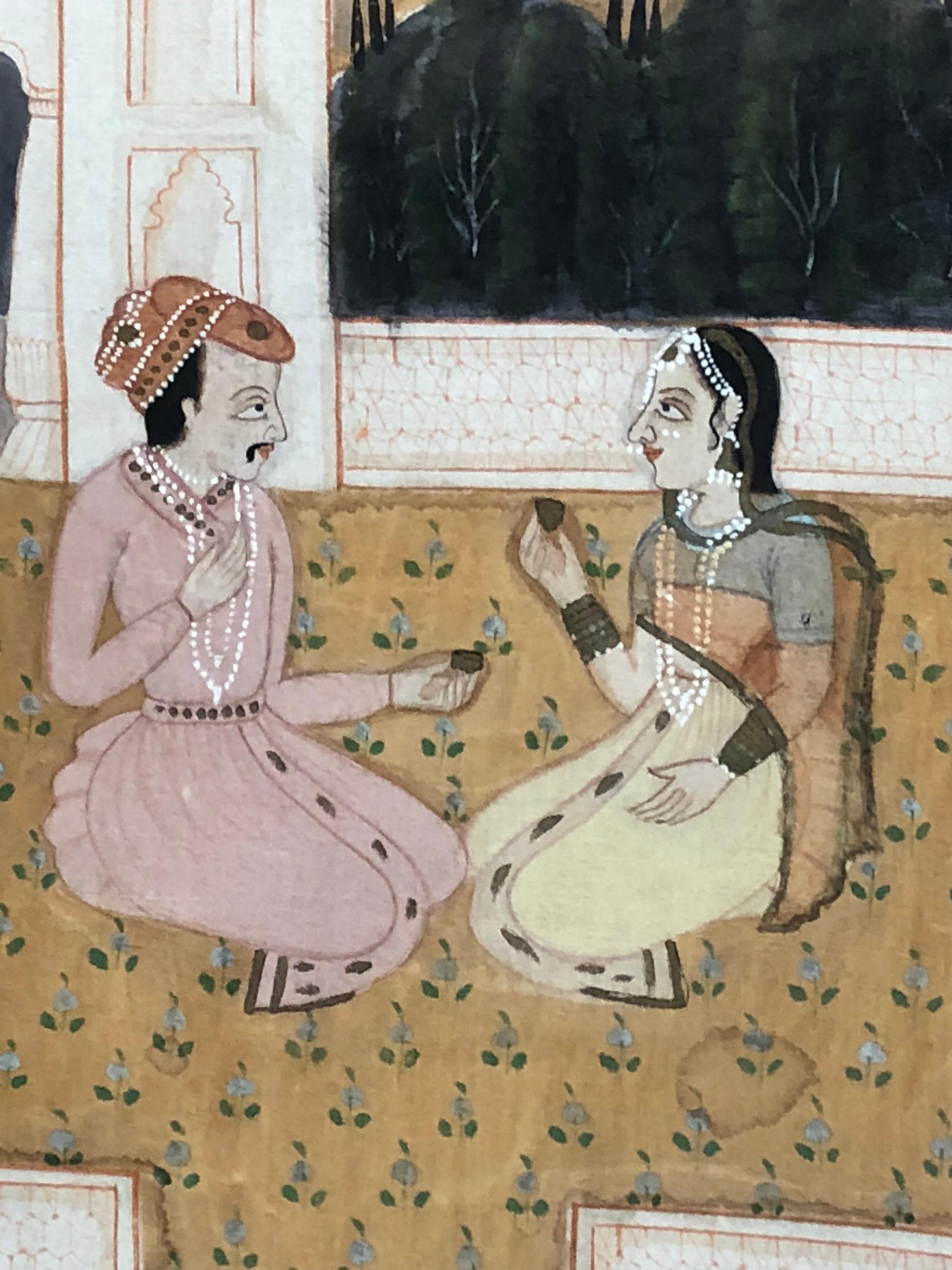 A 19th century painted textile from Rajasthan India, depicting a seated couple exchanging gifts in a courtyard. The colorful and pleasant painting is recently framed behind glass in a brass plated metal frame.