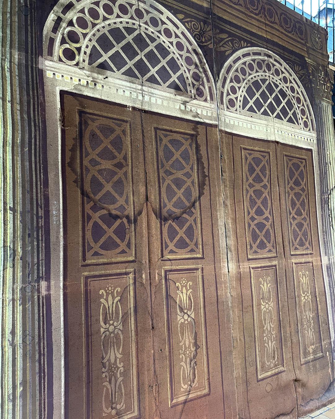 This large-scale antique theater backdrop offers an evocative illusion of neoclassical architecture, featuring grand double doors framed by Corinthian columns and arched fanlights. The trompe-l'œil technique brings depth and grandeur to any space,