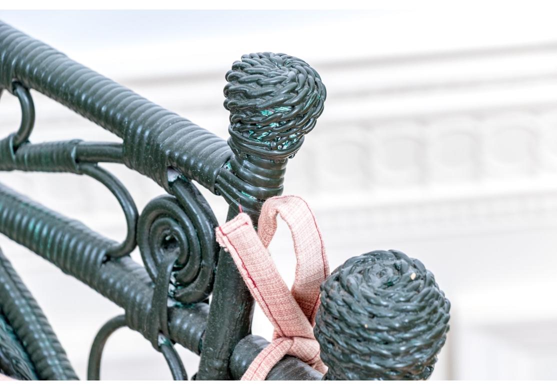 L'ensemble est peint en vert chasseur foncé et est finement ajouré. Le dossier haut du rocking-chair est orné d'un ventilateur avec un motif de poignée digne d'une chaude journée d'été et de quatre fleurons. L'ensemble est orné de volutes et de