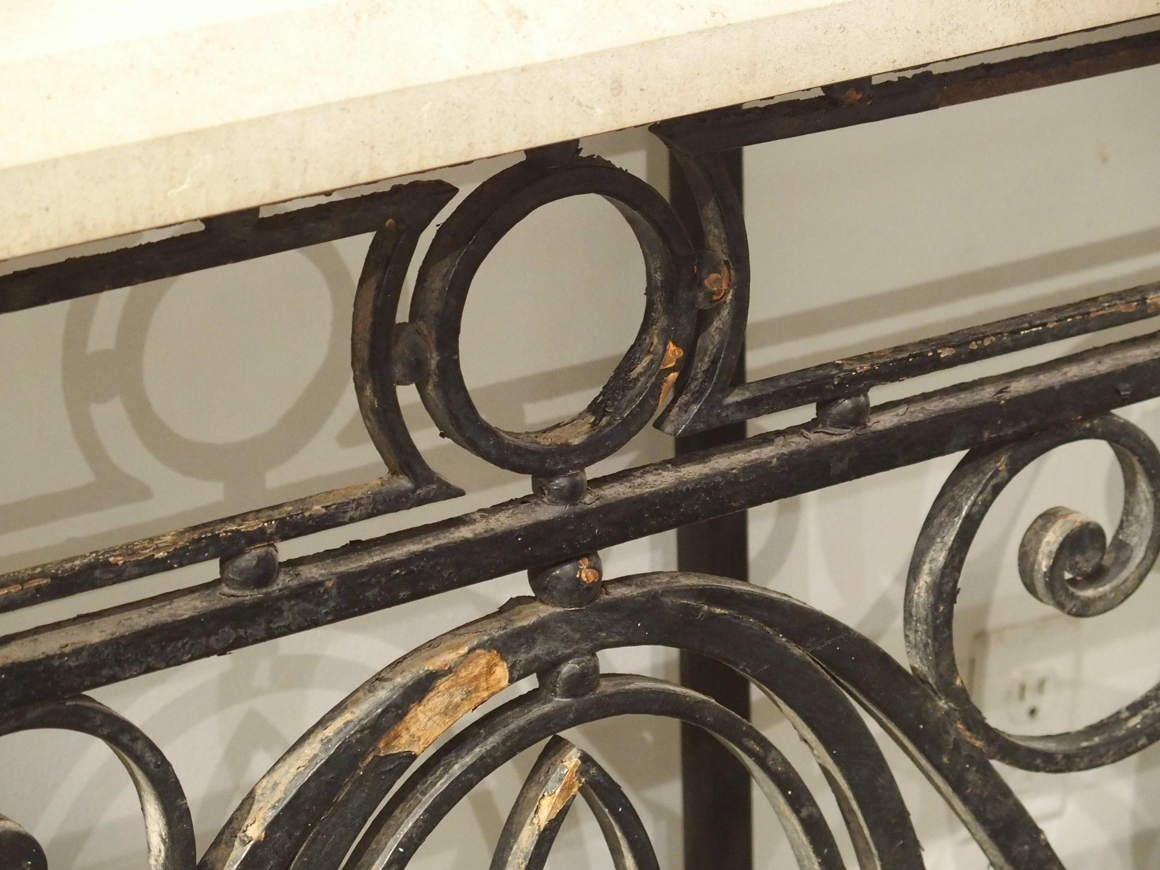 Originally serving as a balcony barrier on a French-style building in Argentina, this wrought iron railing was produced circa 1900. We have repurposed the iron into a console table with a beveled limestone top. At over two inches thick, the hand-cut