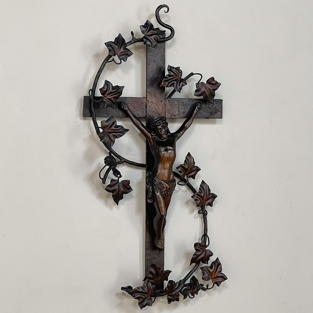 Antique painted wrought iron crucifix is a splendid work designed to last for centuries! The corpus is cast iron, and mounted upon the forged cross with meticulously wrought grapevine and leaves intertwining the work. A subtle bronze colored finish