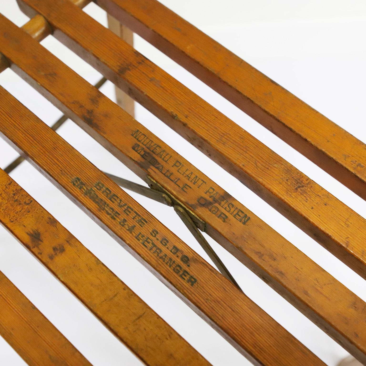 Folding Parisian stool, circa 1920, made in wooden slats marked “Nouveau Pliant Parisien Medaille DÓR” Brevete S.G.D.G. en France & Al,stranger” New folding Parisian, gold medal, patented SGDG France and abroad, small iron handle for transport.