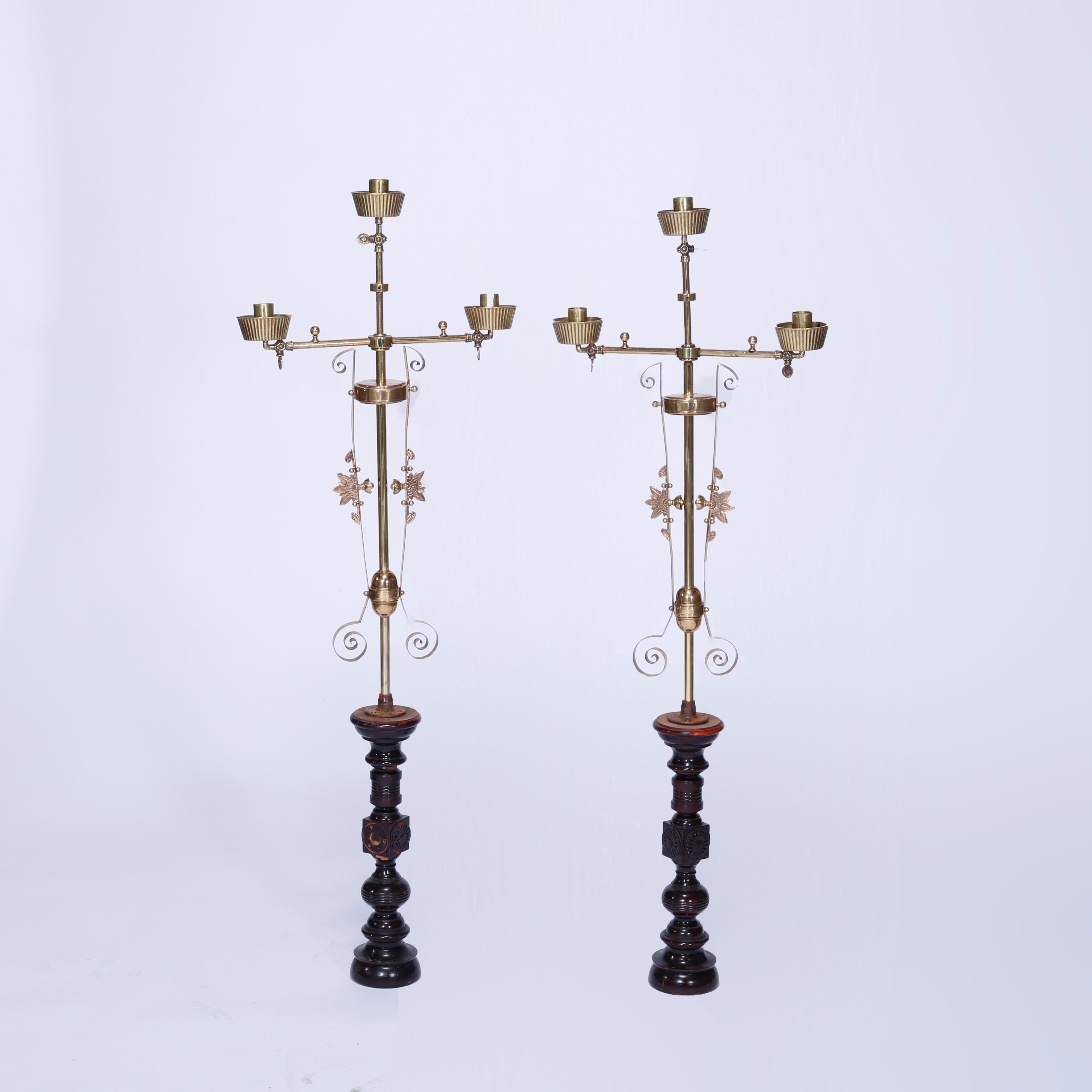 An antique pair of Aesthetic newel post candelabra offer brass construction with three adjustable lights, floral and stylized sunburst elements raised on balustrade mahogany bases having carved rosettes, c1870

Measures- 52'' H x 17.75'' W x 3.5''
