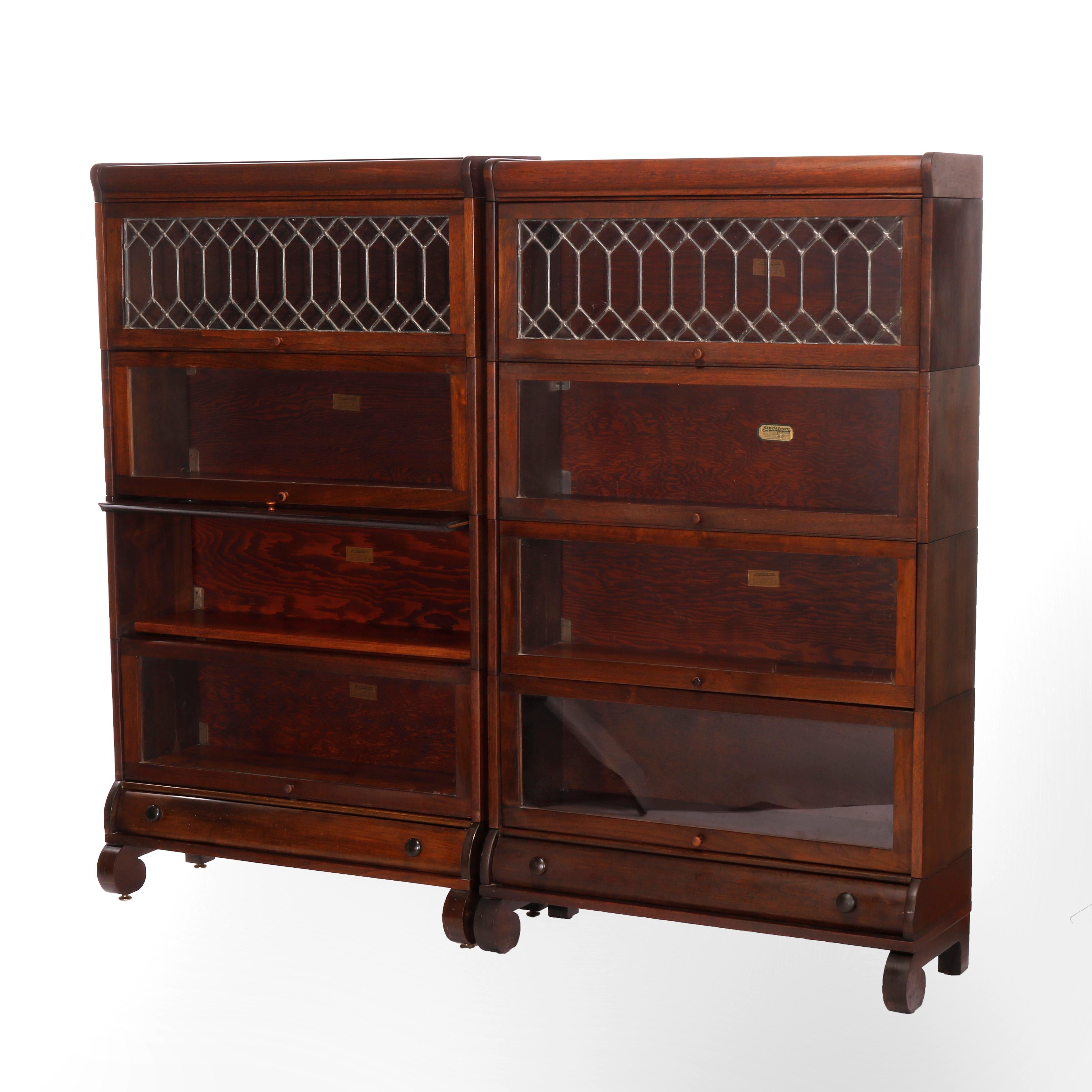 An antique matching pair of Arts and Crafts Barrister bookcases by Lundstrom offers walnut construction with four stacks, each having pull out glass doors with one door having leaded glass and raised on scroll form legs, maker label as photographed,