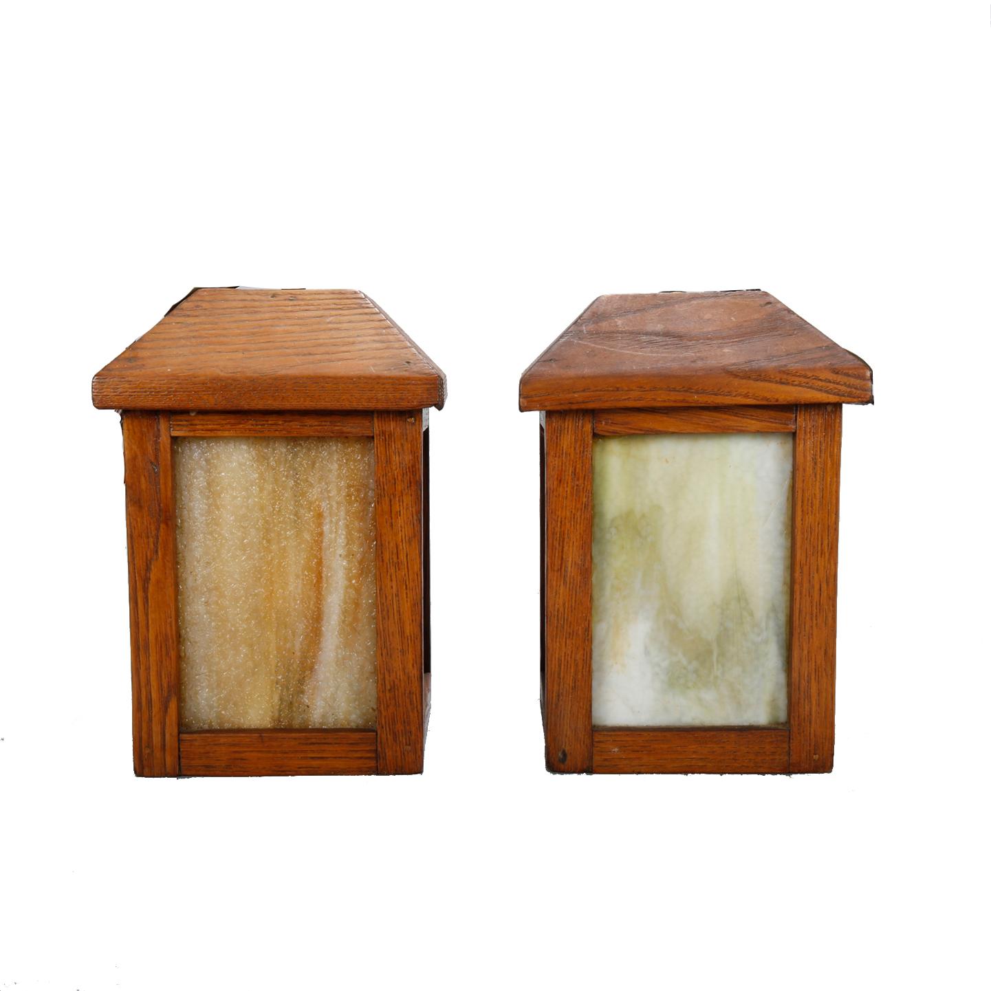 An antique pair of Arts & Crafts Mission hanging lights offer oak construction in lantern form with slag glass panels and single sockets, professionally wired for US electricity, circa 1910.

Measures: 11