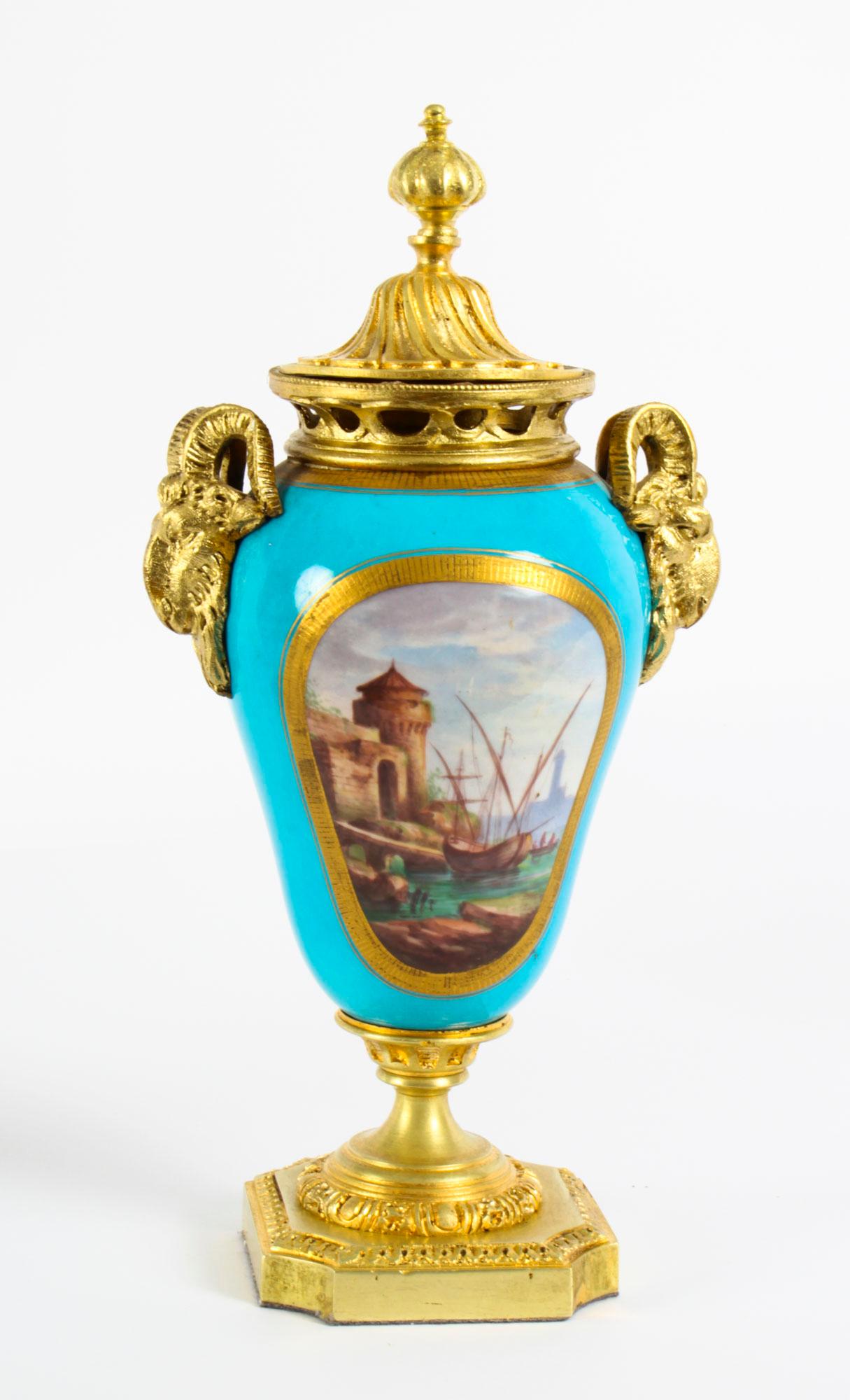 This is a stunning pair of French twin handle ormolu garniture lidded urns with Sèvres hand painted porcelain, circa 1870 in date.

With ecorative ormolu ram head handles and ormolu lids. The porcelain bodies are superbly painted with oval-shaped