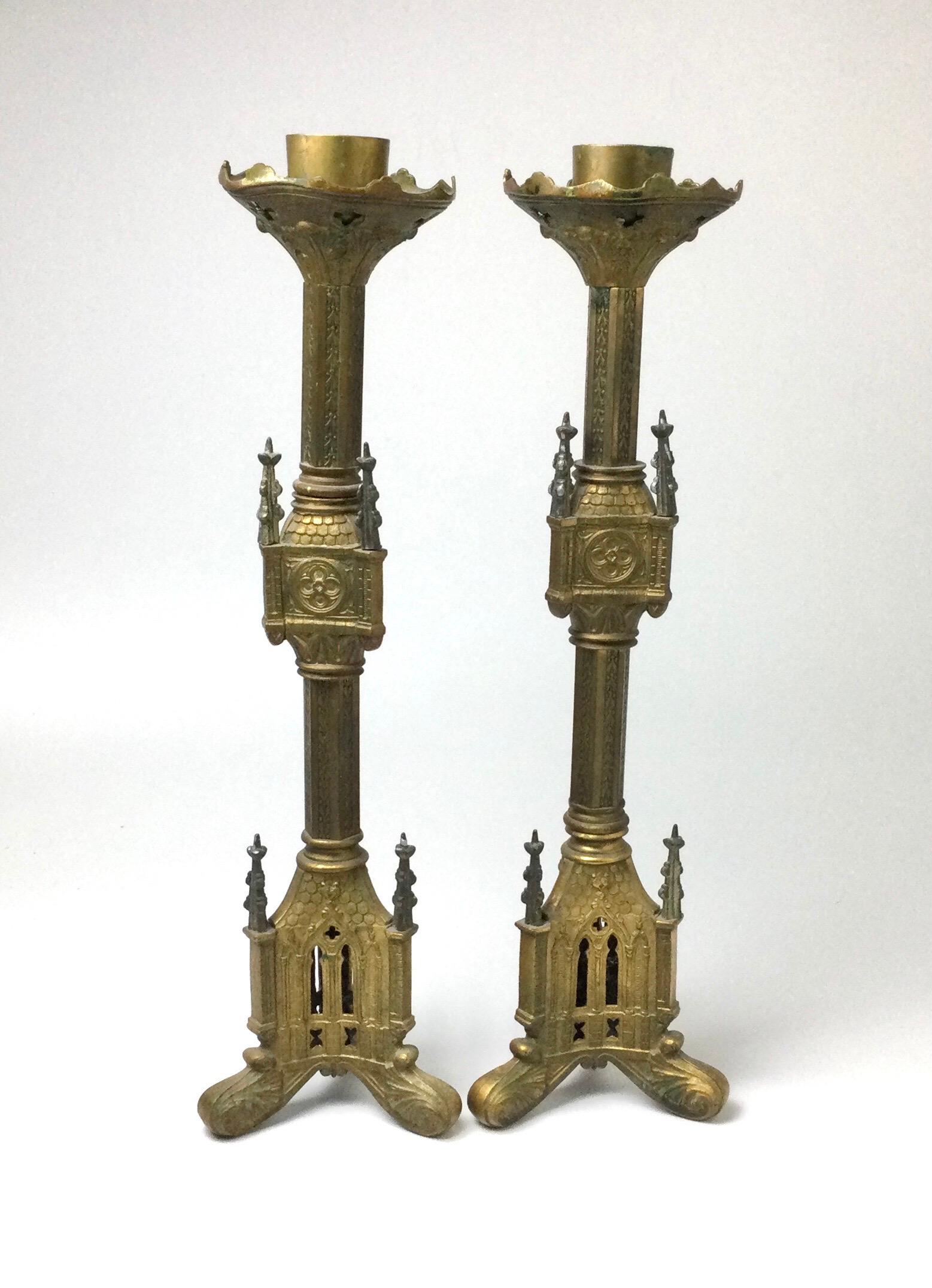 Nice old pair of Gothic Church Alter candlesticks. Nice old patina to the brass from age and use. Some old church was still in the top. Some age appropriate ware from use and age. Small spires are a different metal. Stand 19 1/2