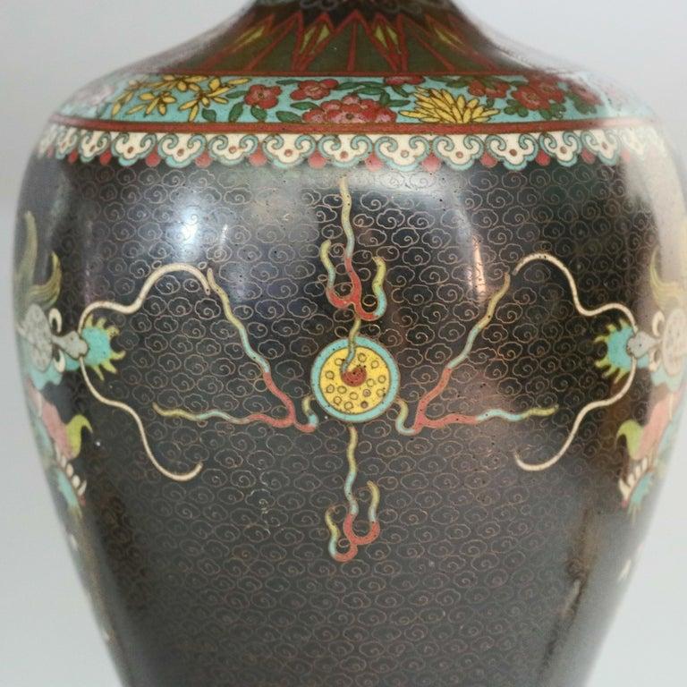 An antique pair of cloisonne table lamps offer urn form with enameled dragon motif against black ground, circa 1920. 

Measures: 28.5