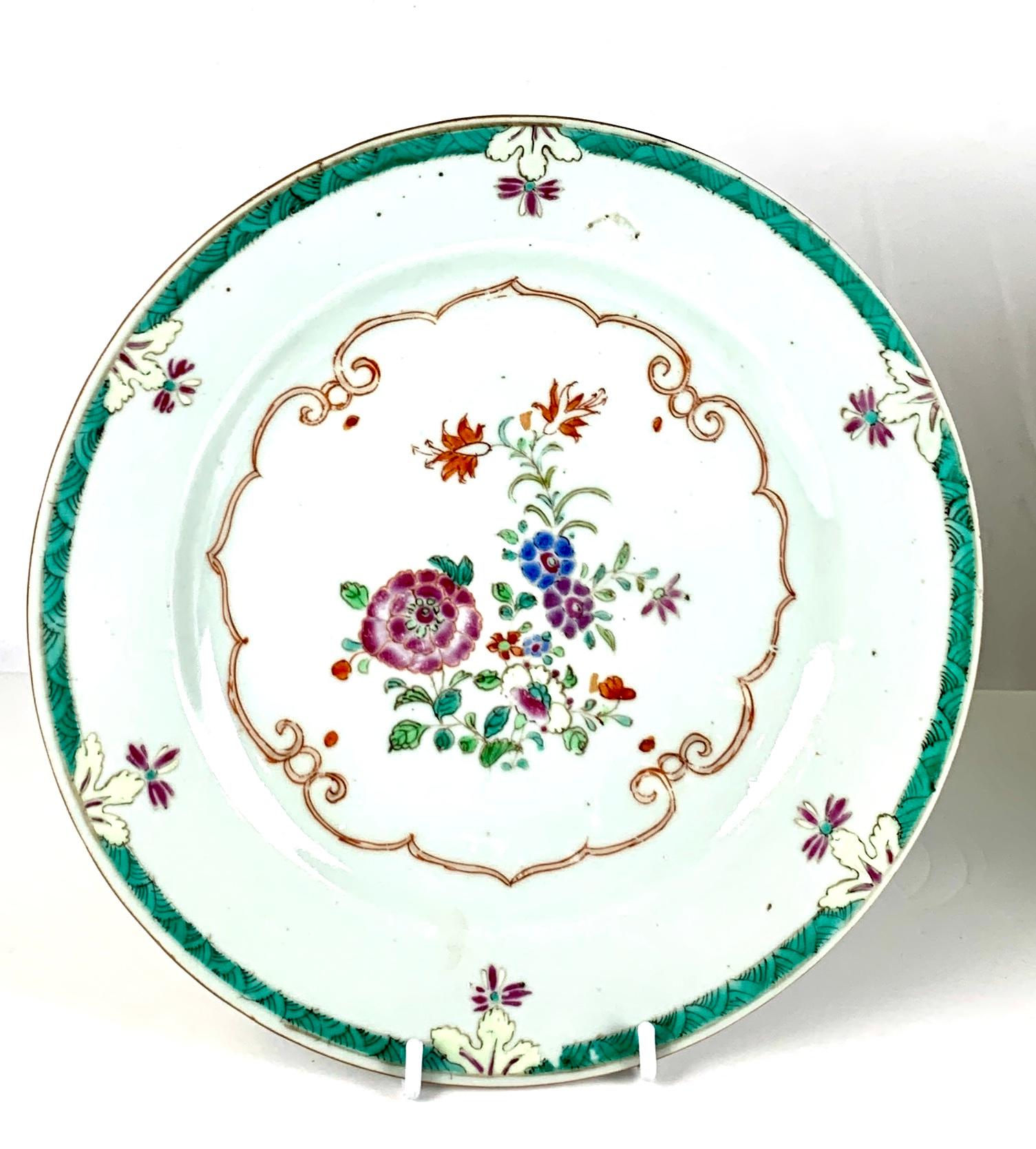 This pair of beautiful Chinese porcelain plates were hand painted in the Famille Rose style in the mid-18th century. 
The center of each plate is painted in delicate colored enamels. 
Many small green leaves enhance lovely flowers painted in purple,