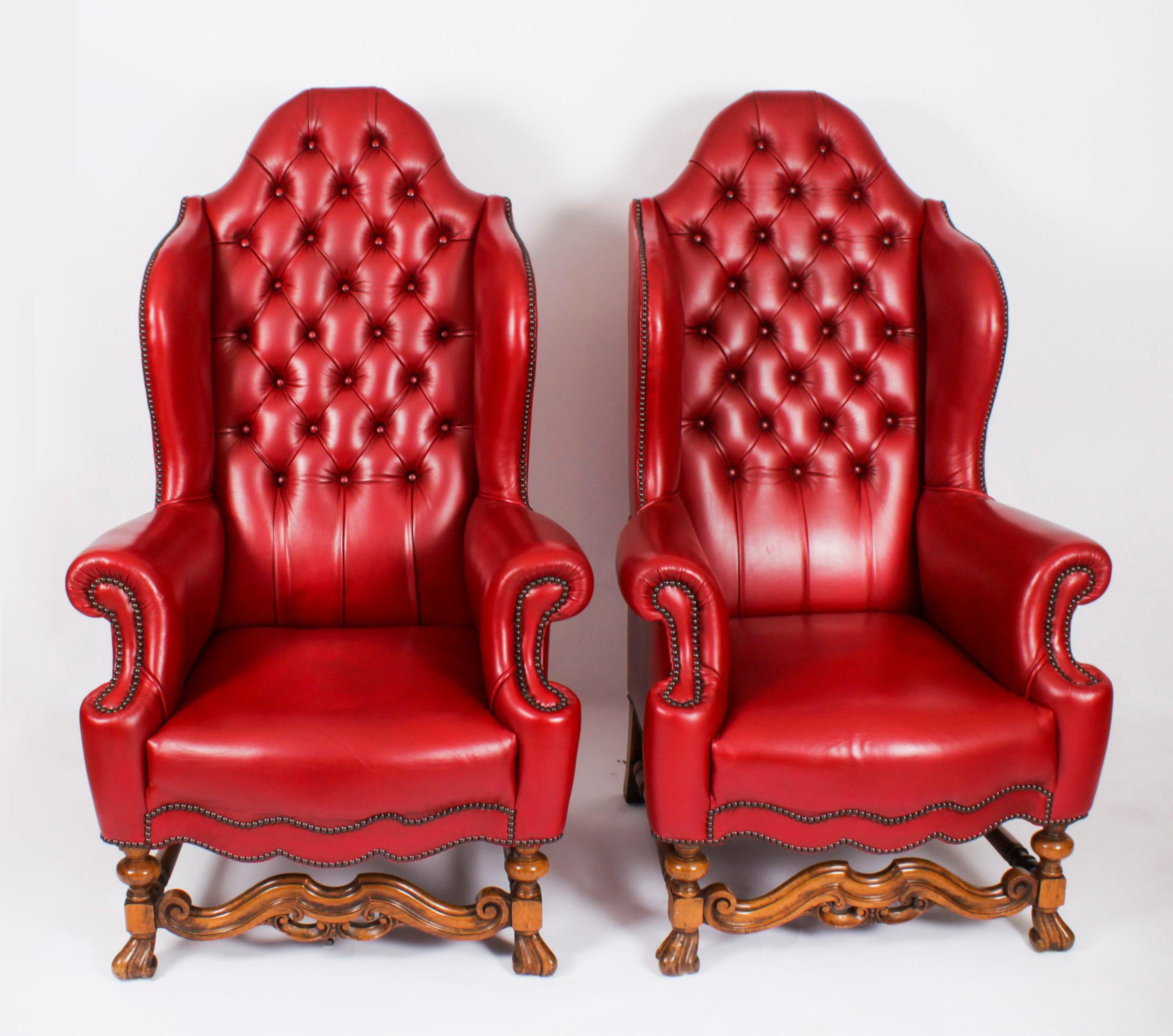 This is an absolutely fabulous pair of antique English button back leather wingback Chippendale Revival throne armchairs, circa 1920 in date.
 
They feature high shaped backs with fitted seat cushions and scrolled arms. They are beautifully raised