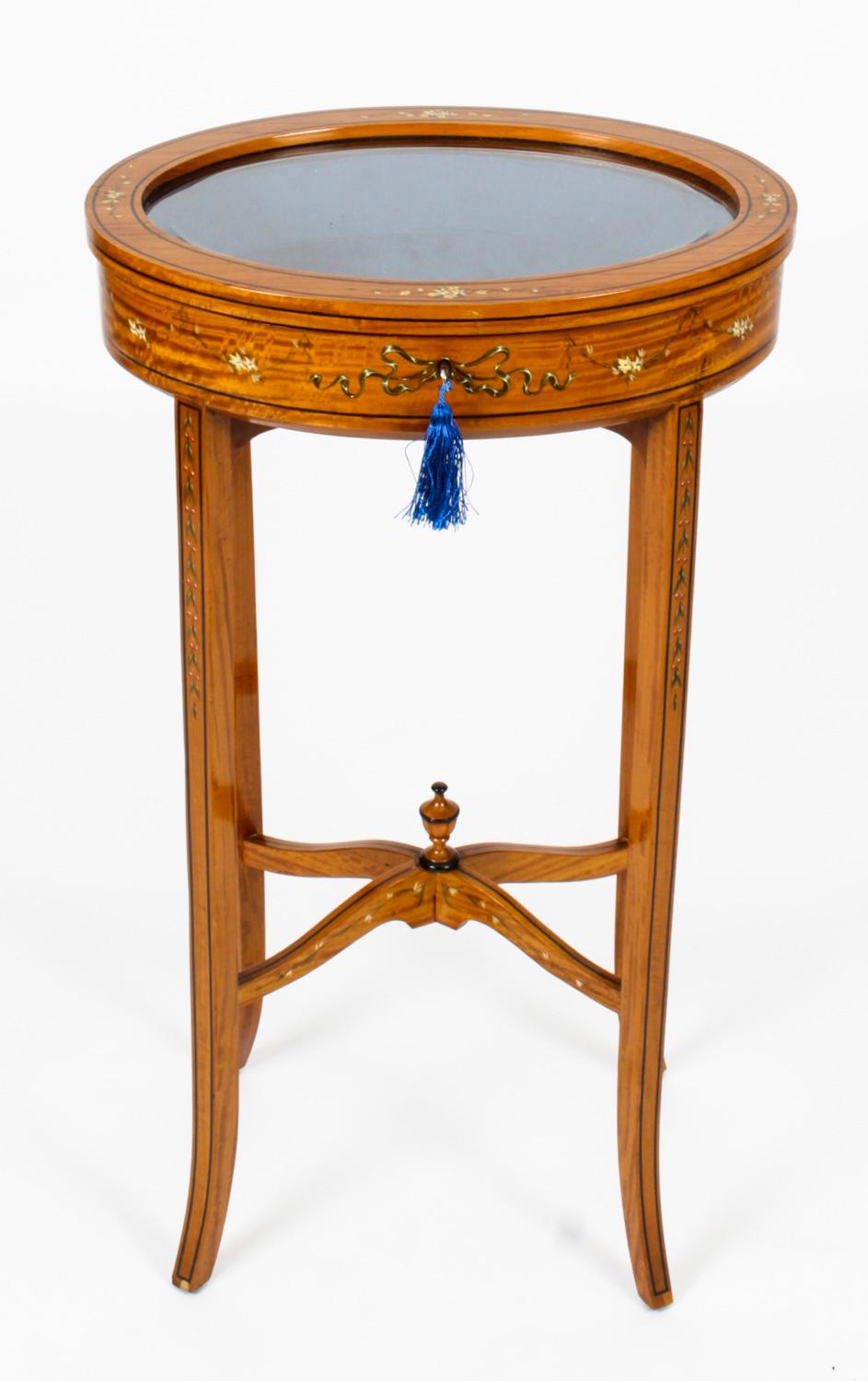 This is a truly beautiful antique pair of Edwardian Satinwood bijouterie display tables, by R. G. Dunn, circa 1900 in date.
 
The oval shaped display tables have hinged glazed lids and are raised on square tapering legs joined by oval under-tiers