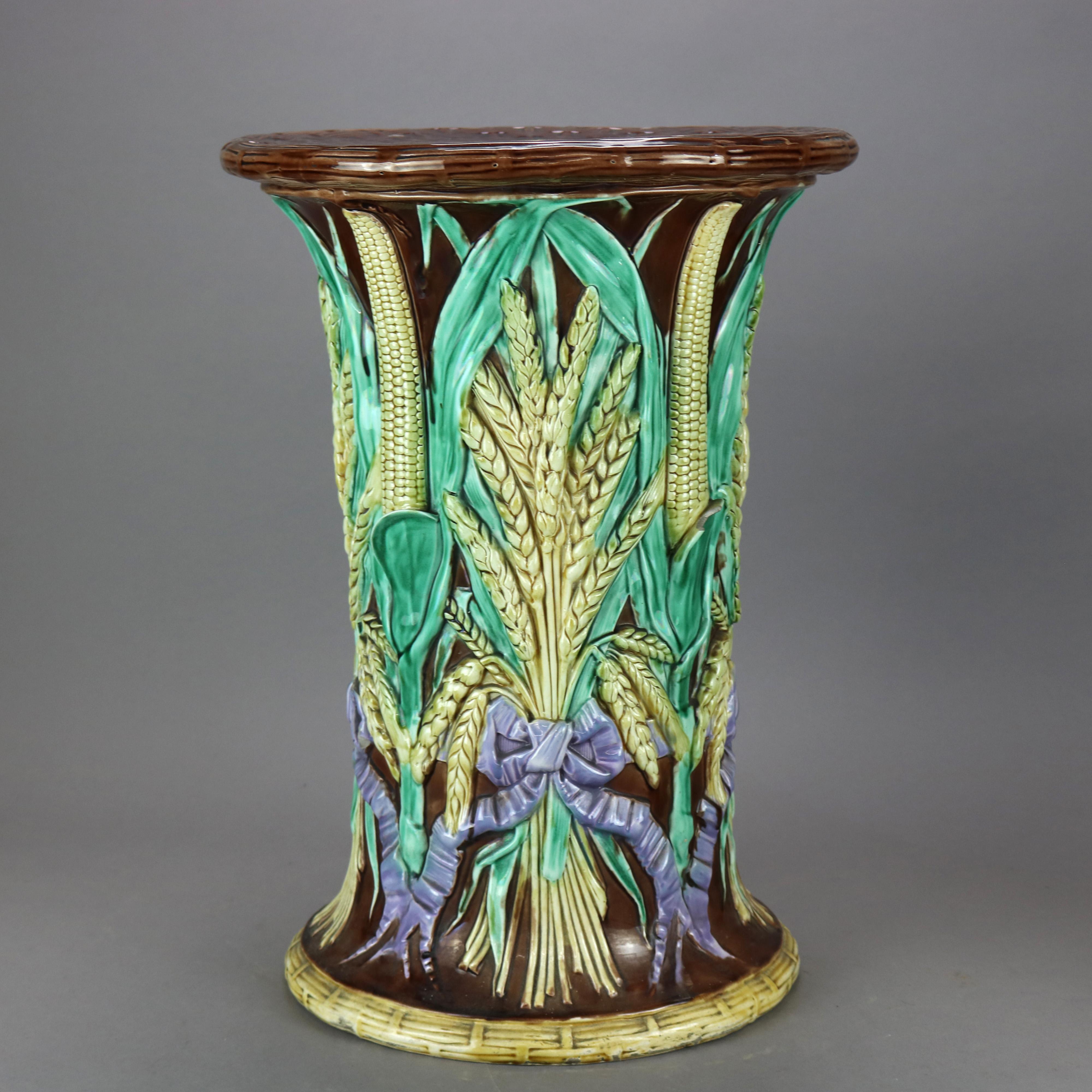 An antique pair of English Majolica harvest garden seats by John Adams. & Co. offer art pottery construction in stylized hour glass form and having basketweave seat with perforated handle over bodice with corn and wheat bundles in relief, unmarked