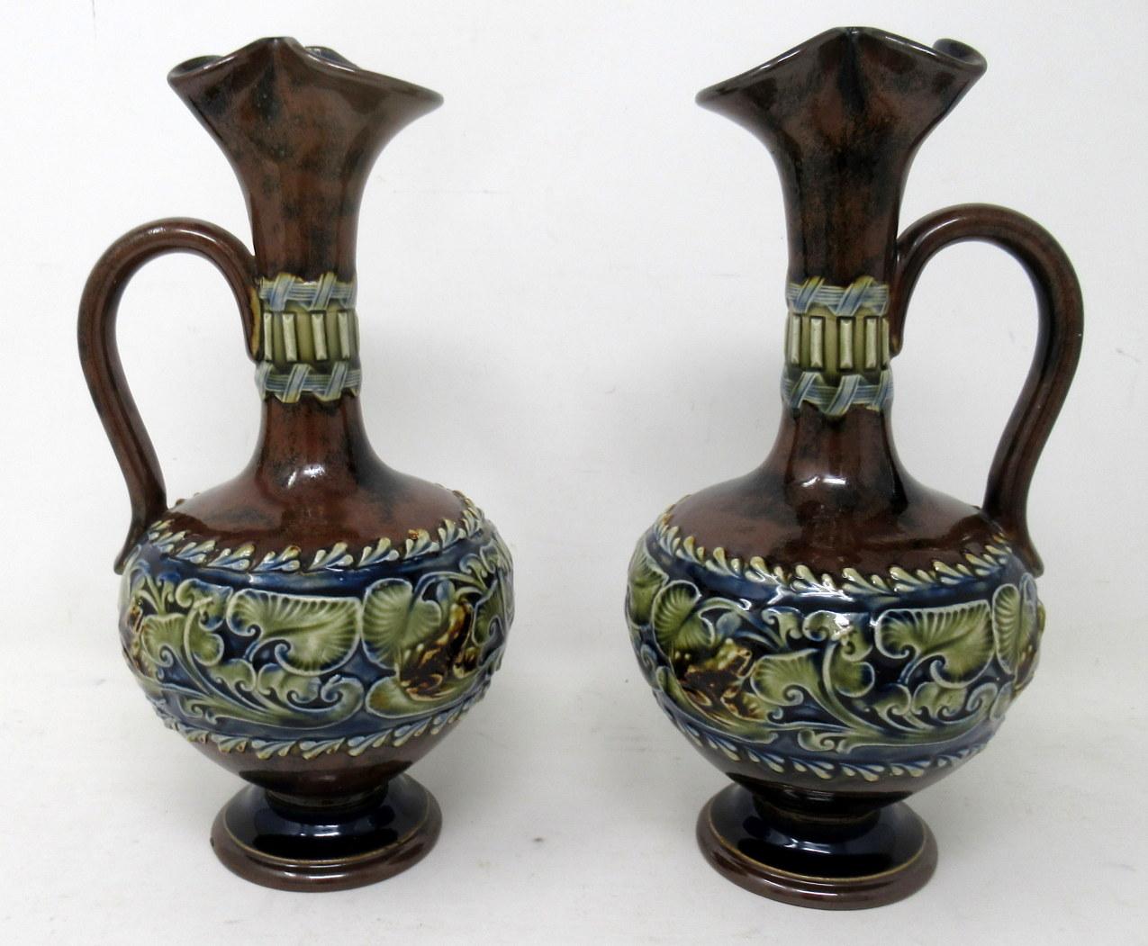 A Very Stylish Identical Pair of English Royal Doulton Lambeth English Moulded Salt-Glaze Stoneware Pottery Ewers of compact proportions. 

Each of bulbous form with wavy flared rim and single scroll handle. Lavish Art Nouveau raised tube-line