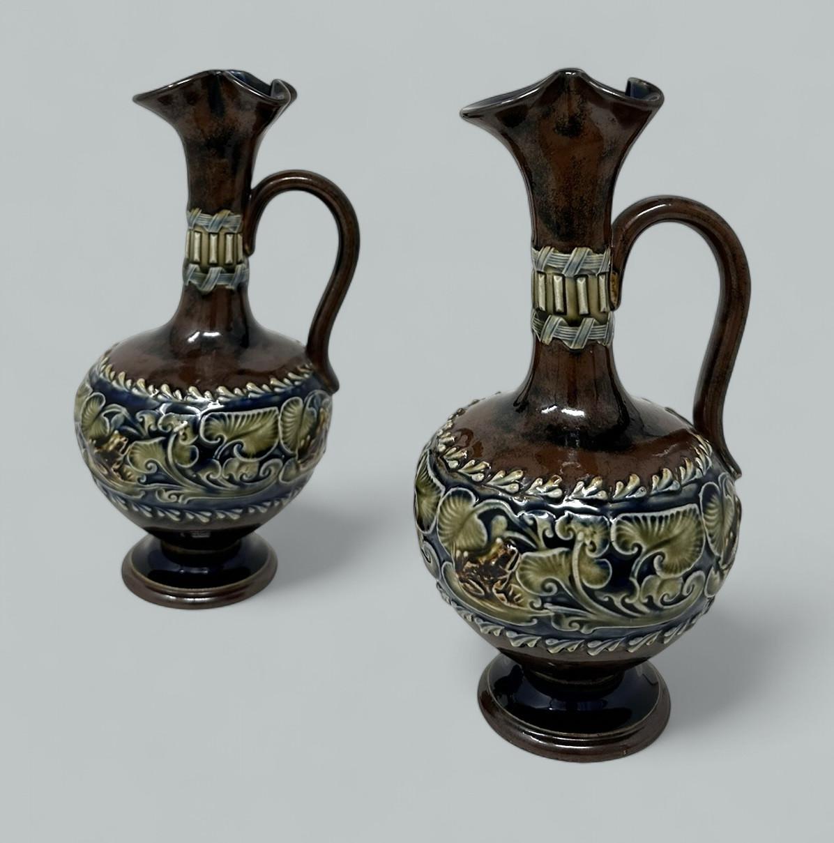 Una coppia identica e di grande stile di vasi in ceramica salata e smaltata di Royal Doulton Lambeth, di proporzioni compatte. 

Ognuno di essi ha una forma bulbosa con bordo svasato ondulato e manico singolo a voluta. Sontuosa decorazione tubolare