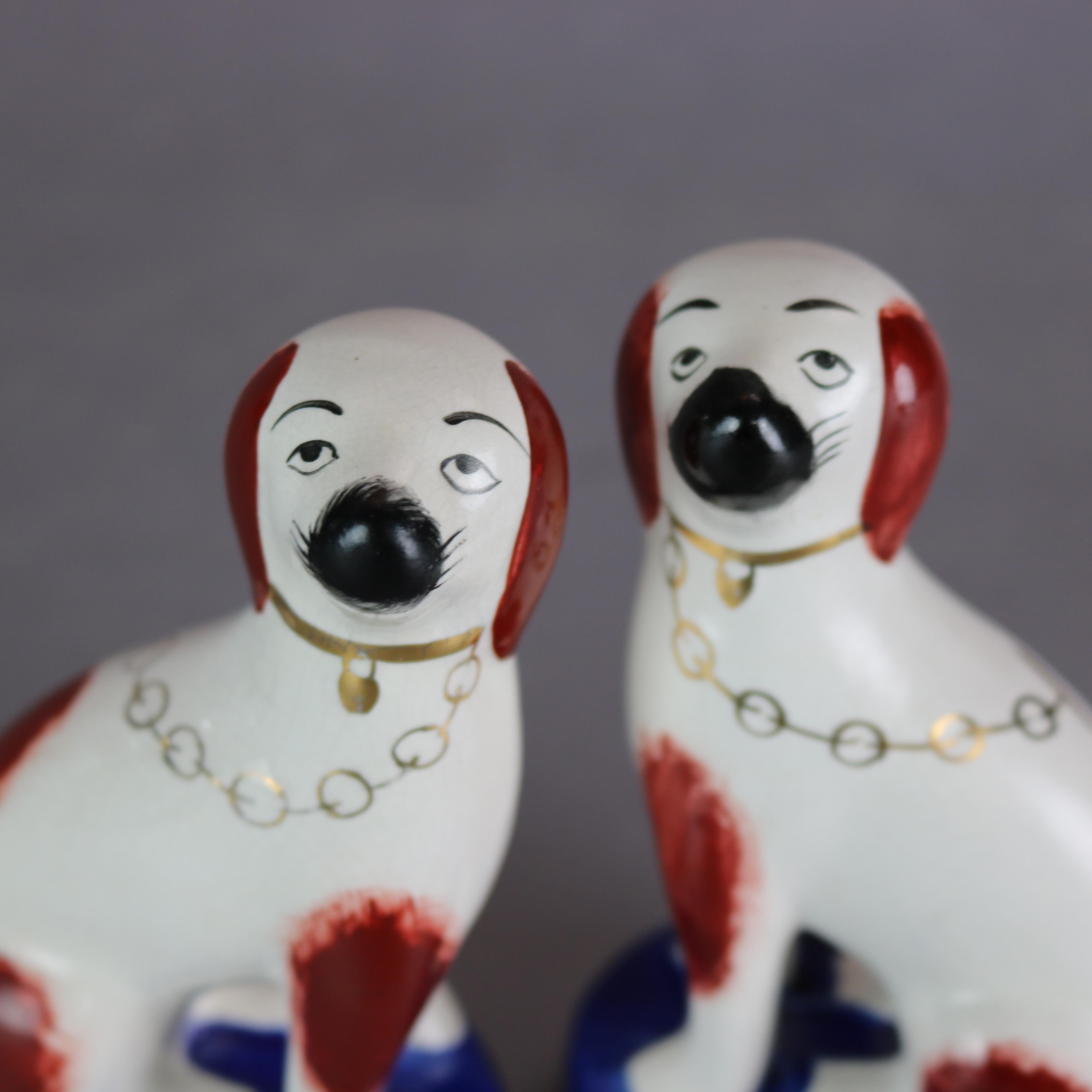 An antique pair of English Staffordshire dogs offer hand painted and gilt pottery slip mold spaniels seated on plinth, unsigned, circa 1900

Measures: 4.75