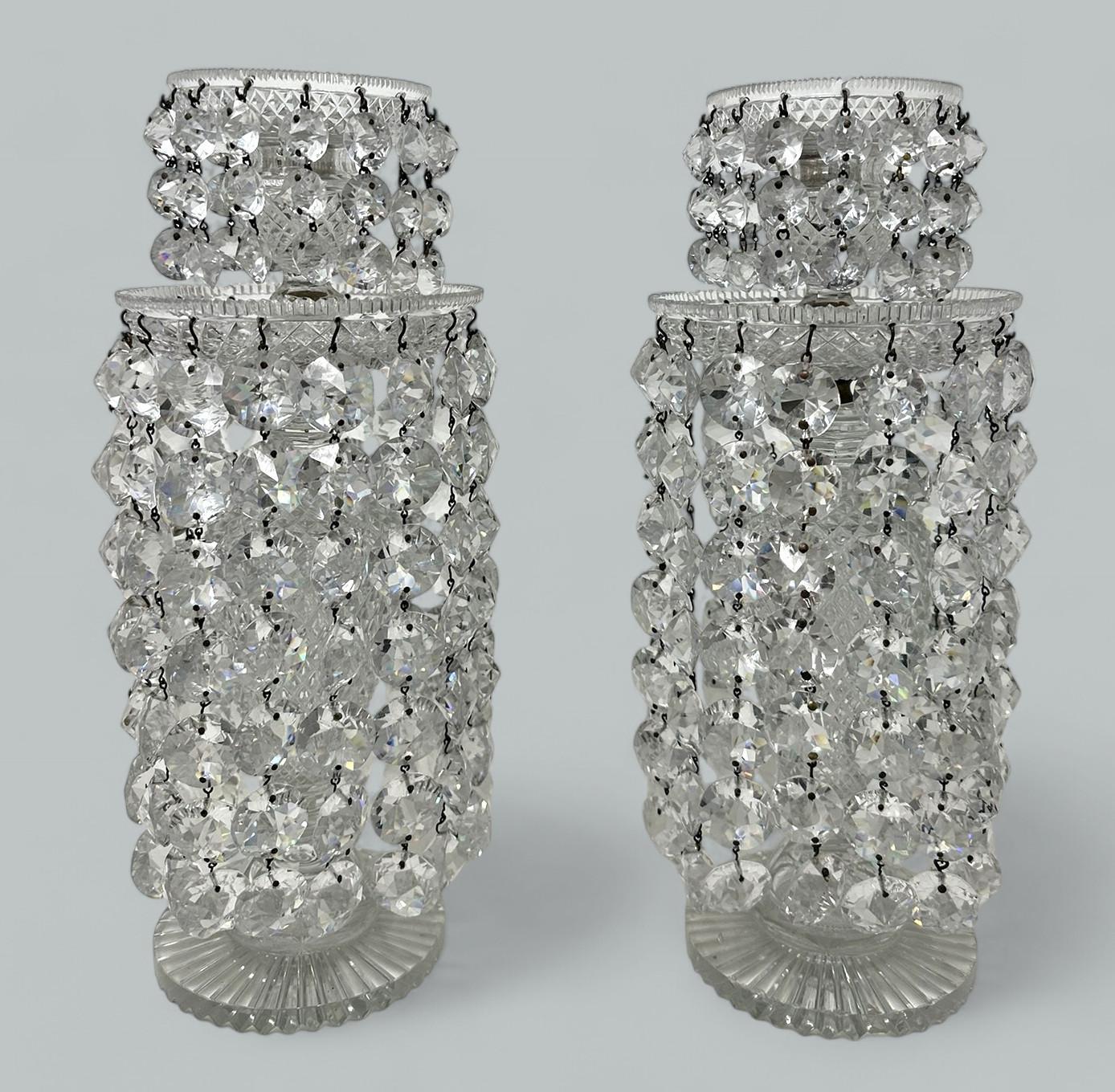 Un esempio eccezionalmente raffinato di una coppia di candelabri neoclassici della prima Reggenza inglese a una luce e a due livelli in cristallo al piombo tagliato a mano Lustre di london con colonne tagliate a diamante sopra basi circolari