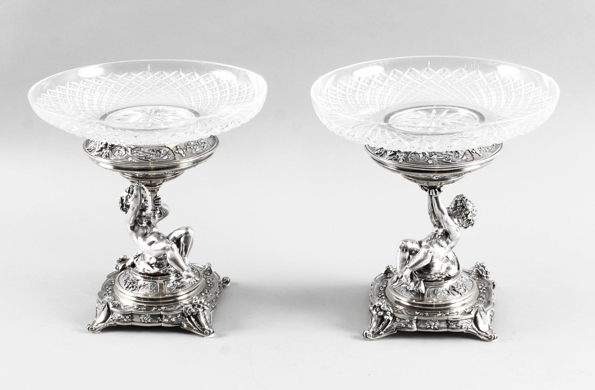 This is an intricate and exquisitely made antique pair of English Victorian parcel gilt silver plated and cut glass centrepieces by the renowned silversmiths Elkington & Co., dated 1883.
 
Each of these stunning centrepieces has a wonderful