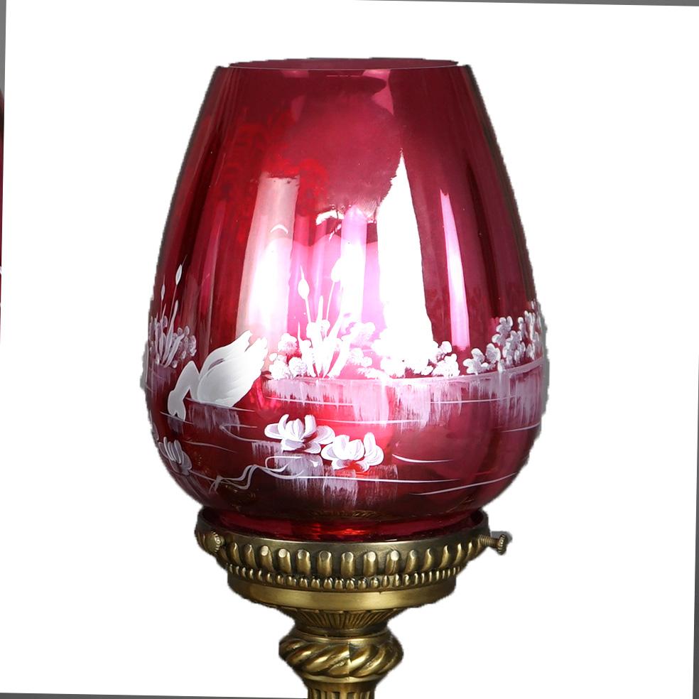 An antique pair of Fenton Mary Gregory table lamps with cranberry glass shades having enameled lake scene with swans, raised on bronzed metal bases, circa 1940 

Measure - 13