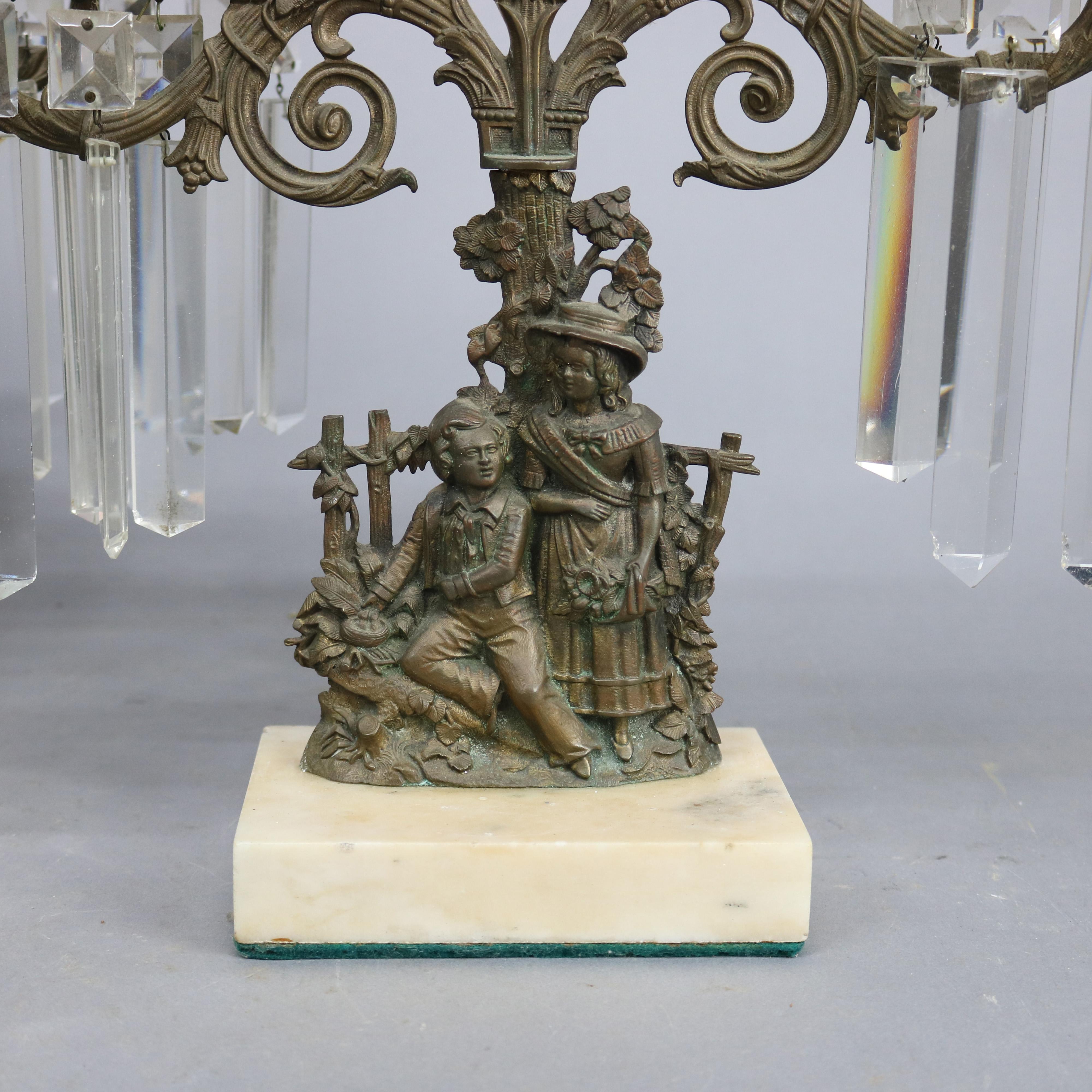An antique pair of figural candelabra offer three arm cast brass frame with a girl and boy in countryside setting, seated on marble base with crystal highlights throughout, 20th century

Measures: 16