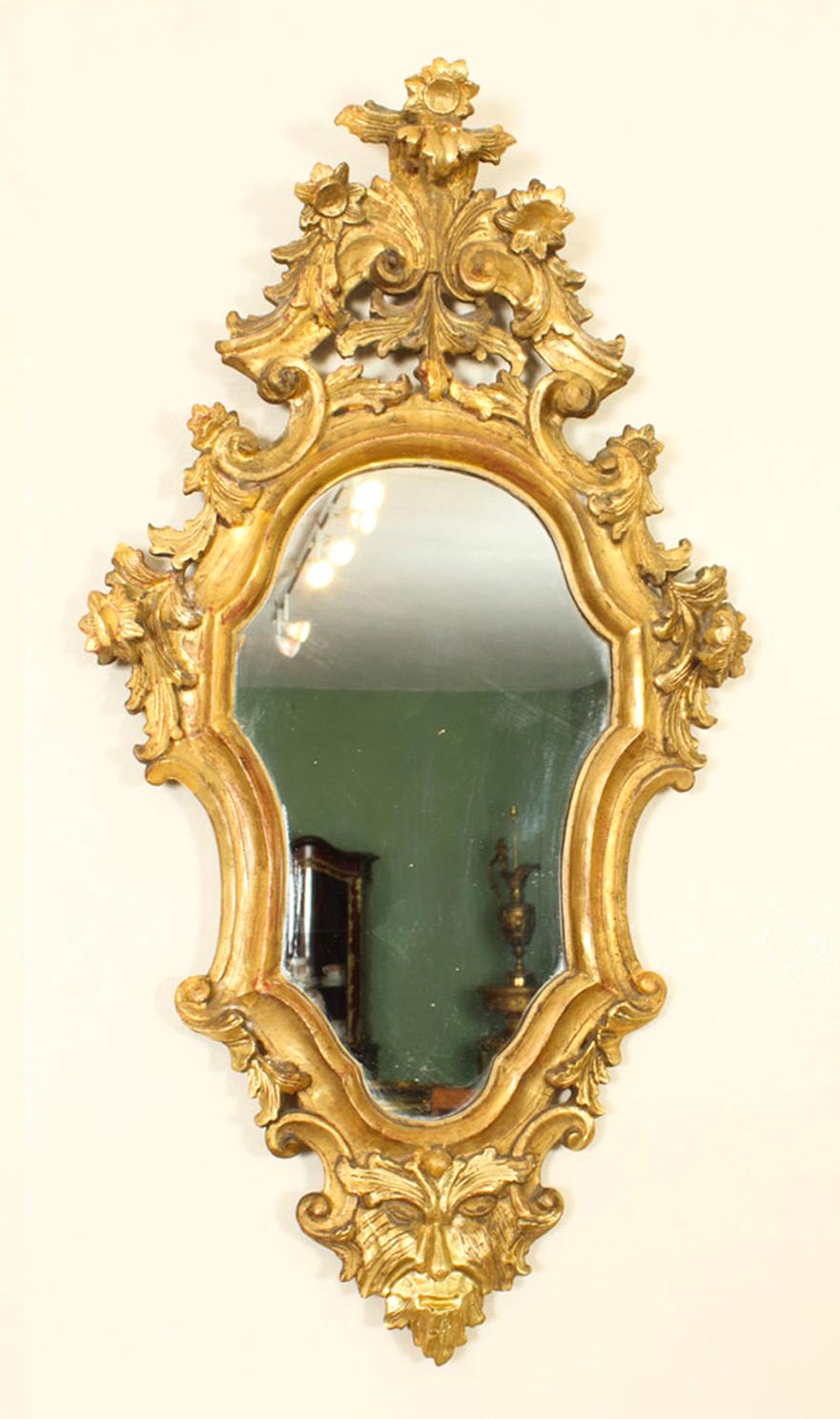 This is a superb pair of antique Italian Florentine  giltwood mirrors, circa 1870 in date.

The shaped mirrors plates are set within a Rococo boldly-carved S scroll and mask frame, and they retain the original gilding.

Florentine style refers to