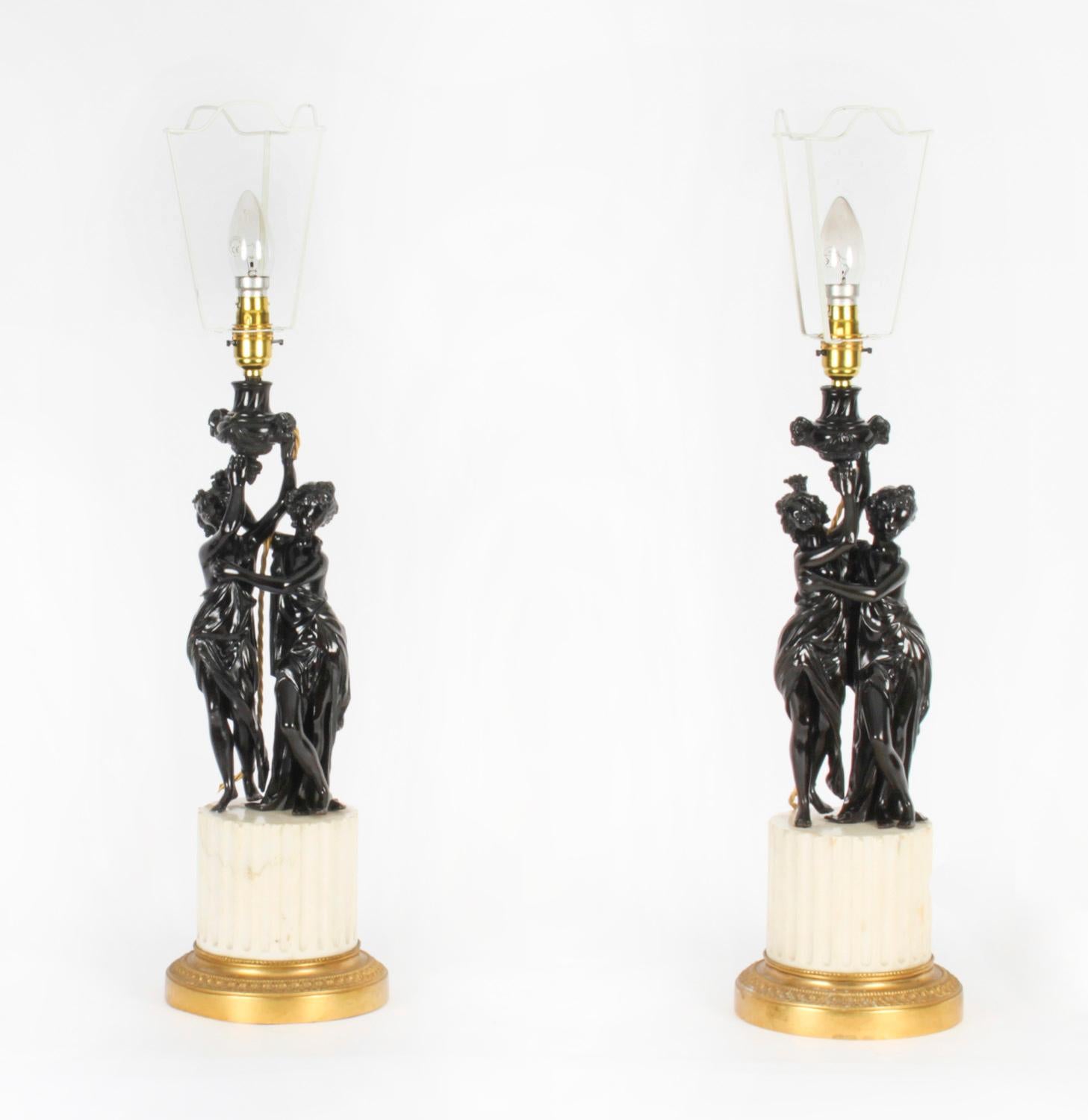 An antique pair of French bronze and marble louis Revival table lamps, Circa 1880 in date.

Each lamps features a pair of maidens in classical costumes raised on fluted white marble column plinth bases with gilt ormolu laurel leaf stands and