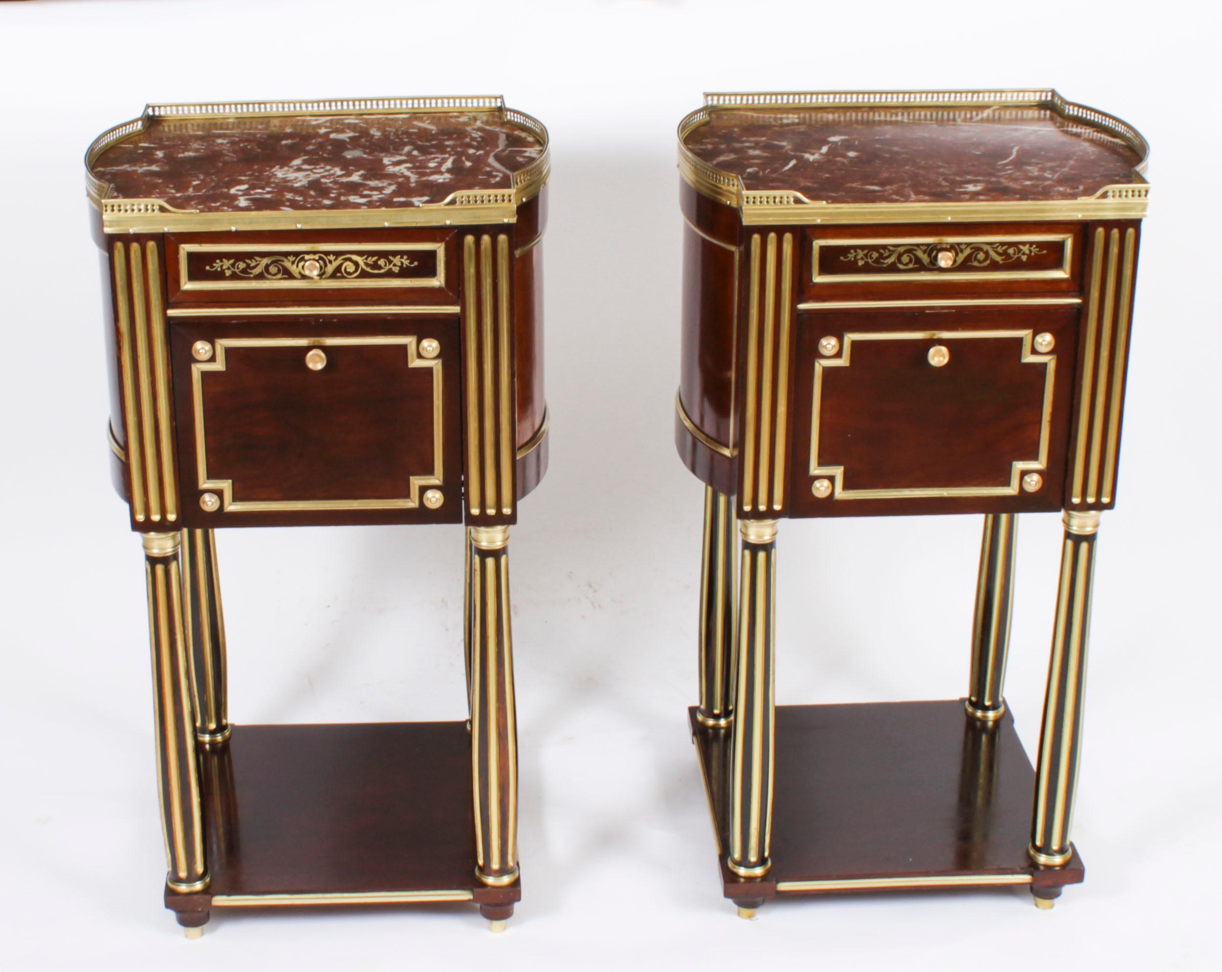 A thoroughly delightful pair of antique French Empire brass inlaid flame mahogany bedside cabinets, circa 1830 in date.

They are freestanding and finished on all four sides. They each feature bombe' sides and shaped rectangular mottled Rouge de