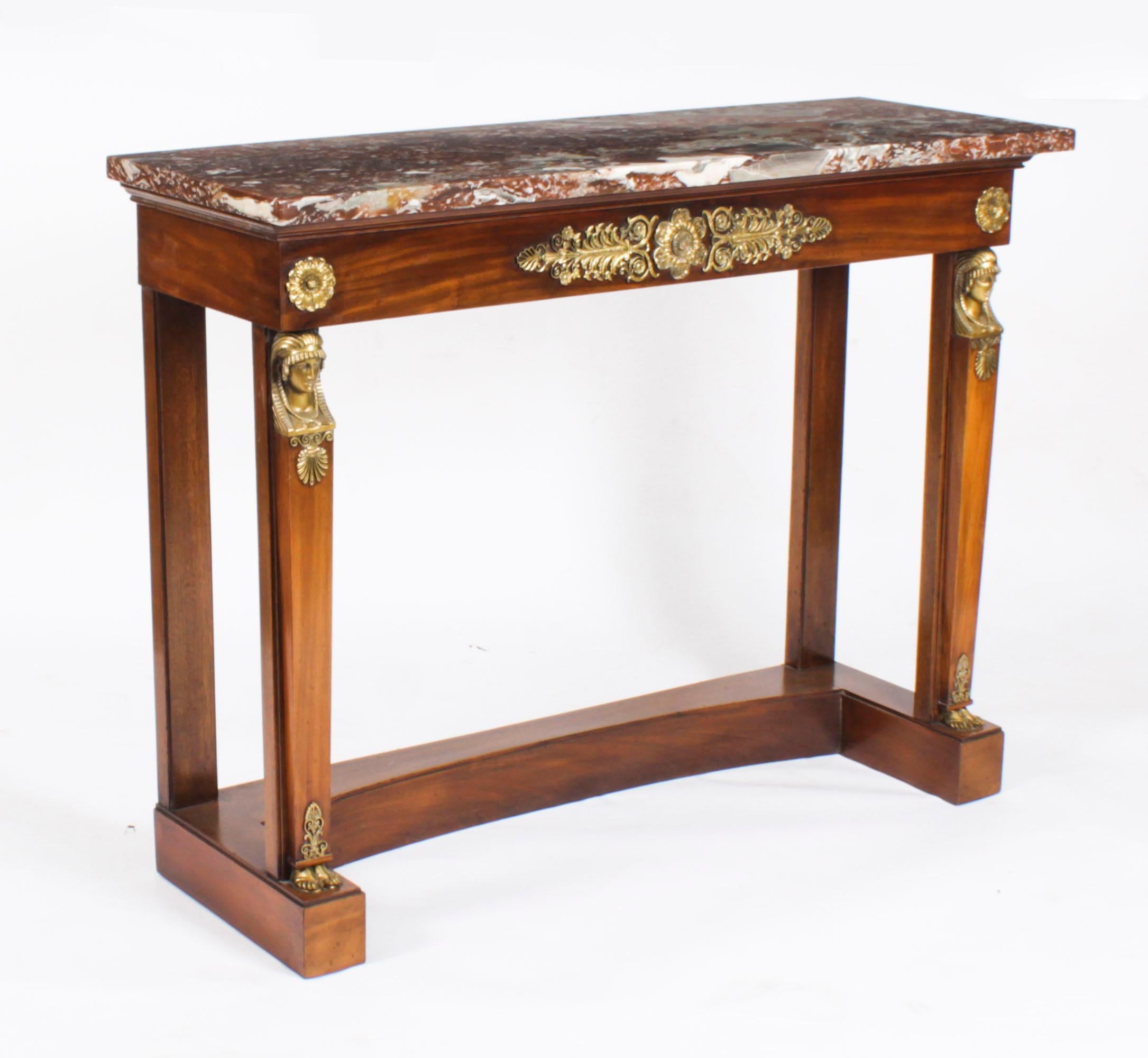 This is a fine antique pair of French Empire marble topped and ormolu mounted flame mahogany console tables,  Circa 1840 in date.
 
Each with a rectangular breche violette marble top over a frieze decorated with ormolu rosettes and palmette mounts