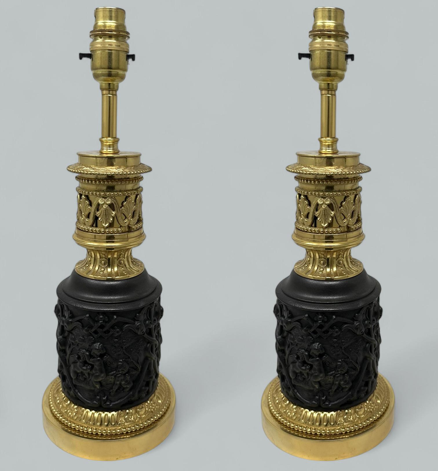 An Exceptionally Fine Pair French Finely Cast Patinated Dark Brown Bronze Fluid Oil Table Lamps of compact proportions, depicting Neoclassical Scenes of Cherubs with scrolling details and stylish beaded rims, now converted to electricity.  

The