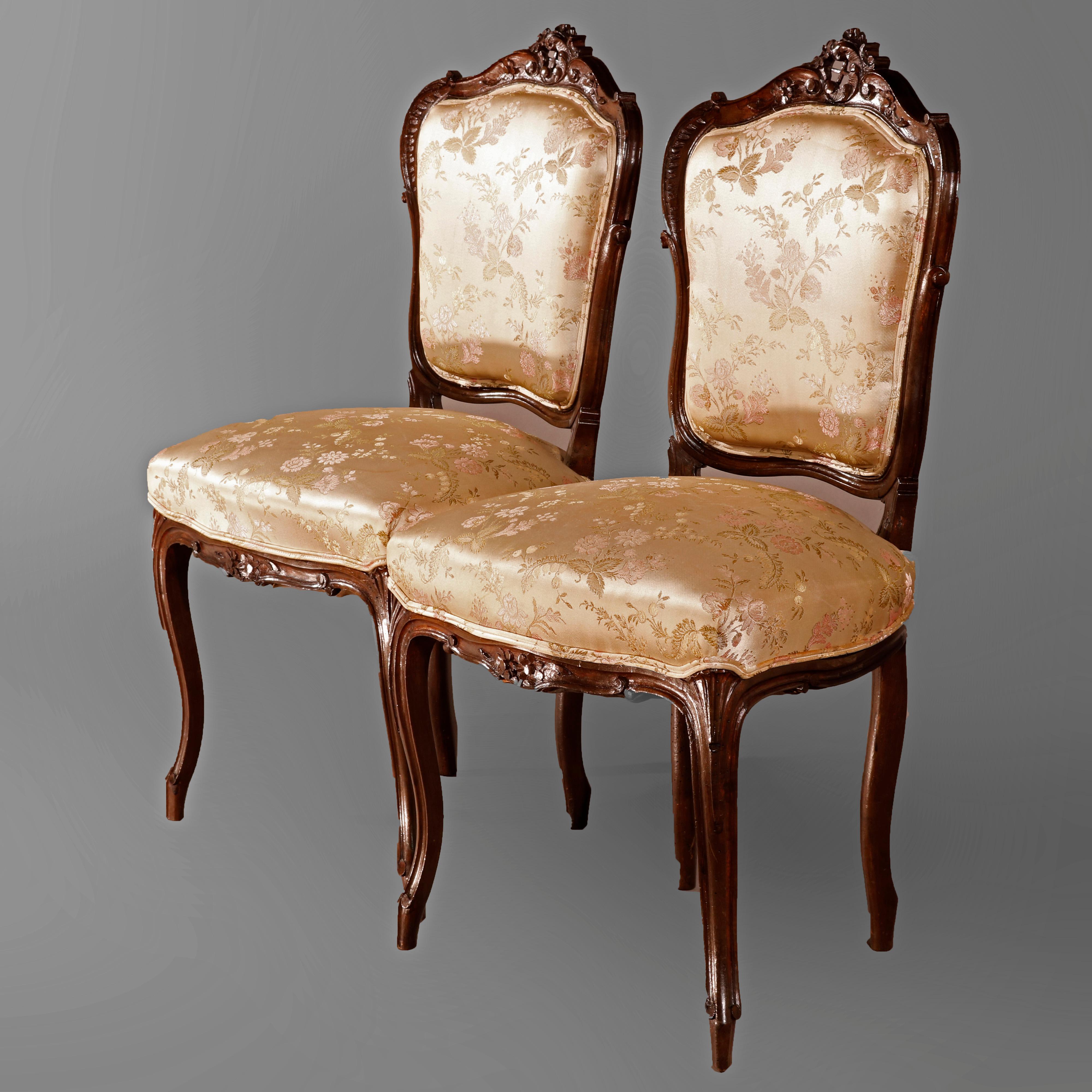An antique pair of French Louis XV style parlor side chairs offer walnut frames with carved foliate crests surmounting upholstered backs and seats, raised on cabriole legs, circa 1890

Measures: 36