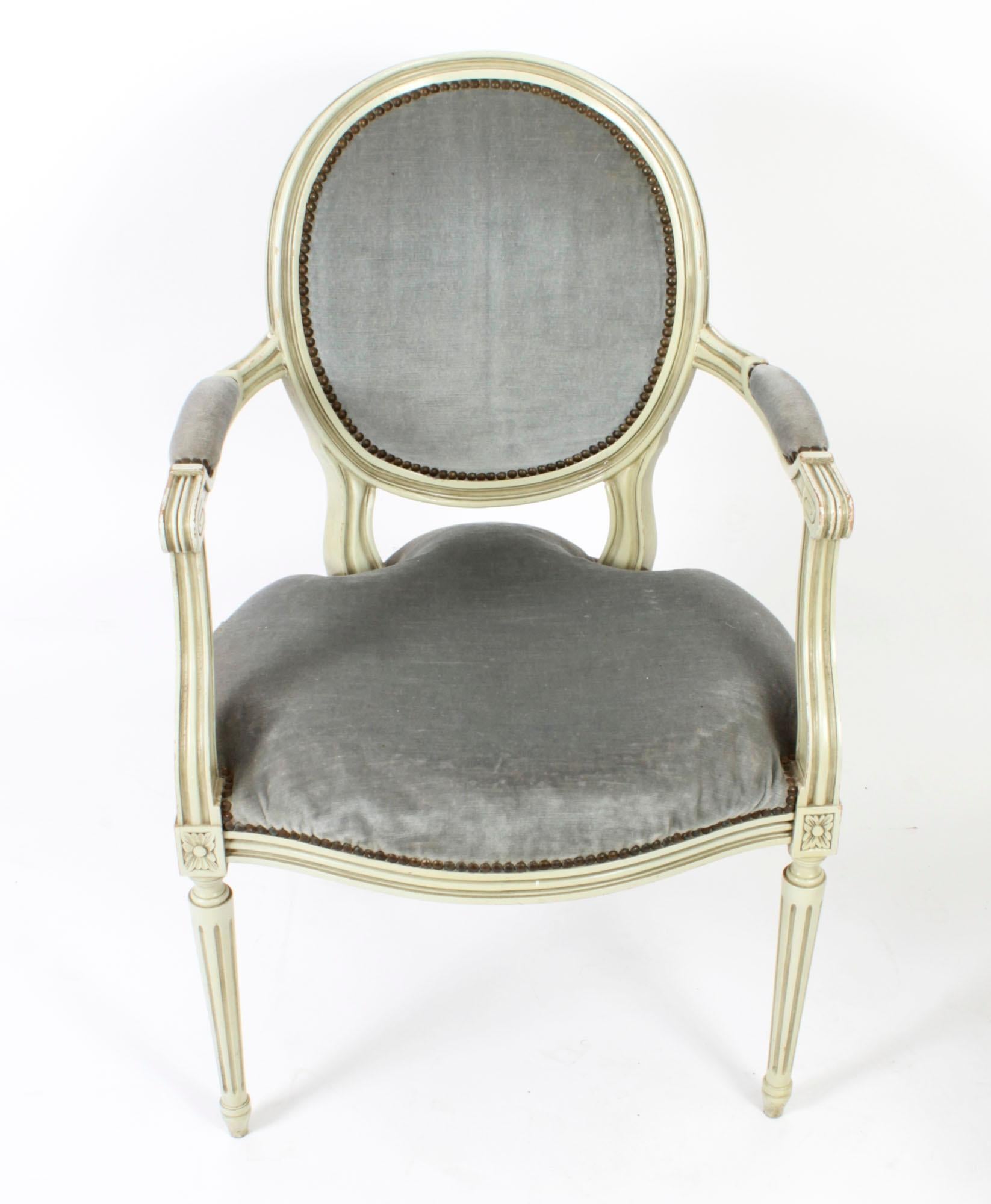 This is a fantastic antique pair of English Sheraton Revival grey/green painted armchairs, circa 1920 in date.
 
Each chair features an oval padded back, with padded seat and padded arms, raised on circulat turned and fluted tapering legs ending