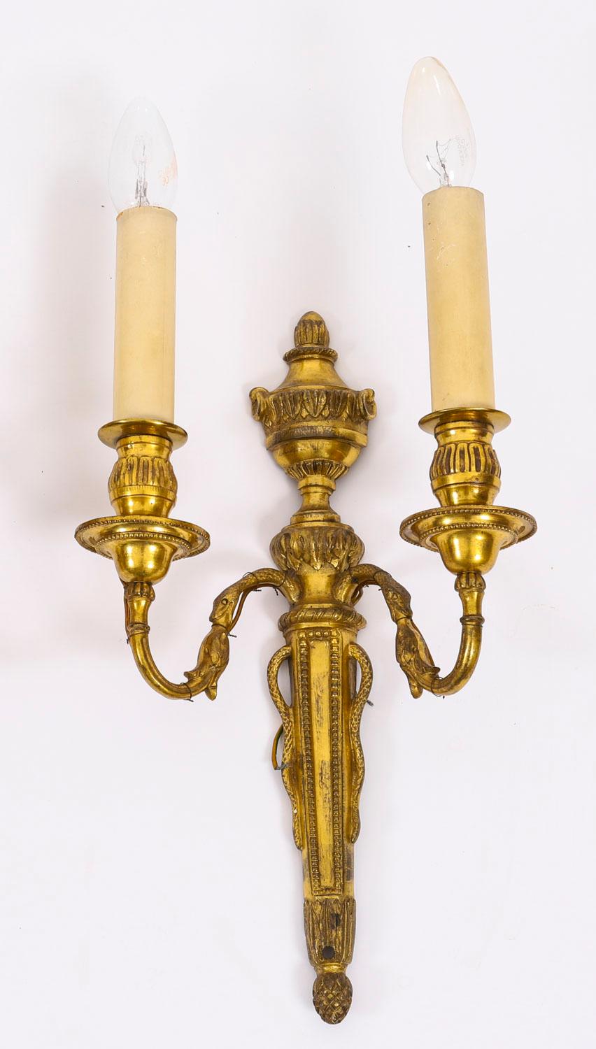 Il s'agit d'une paire d'appliques anciennes néoclassiques françaises à deux branches en bronze doré, datant d'environ 1880.

Les appliques présentent des plaques de fond effilées avec des fleurons en forme d'urnes sur lesquels sont posés des