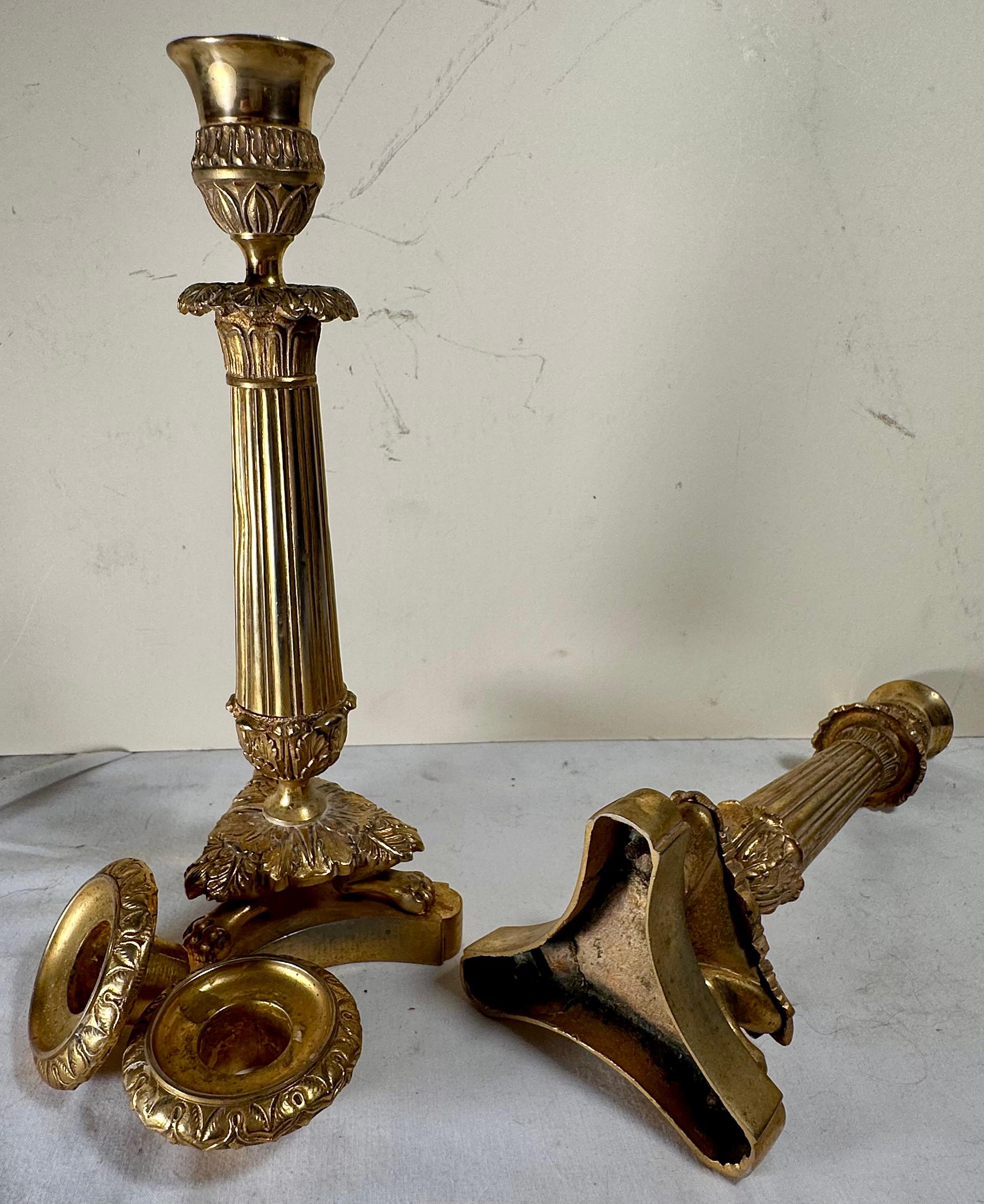 Coppia di candelabri francesi neoclassici in bronzo ormolinato 

Elegante coppia di portacandele a luce singola in bronzo ormoluto francese del XIX secolo. I fusti scanalati e affusolati con collari d'acanto e piedi a zampa su basi concave a forma