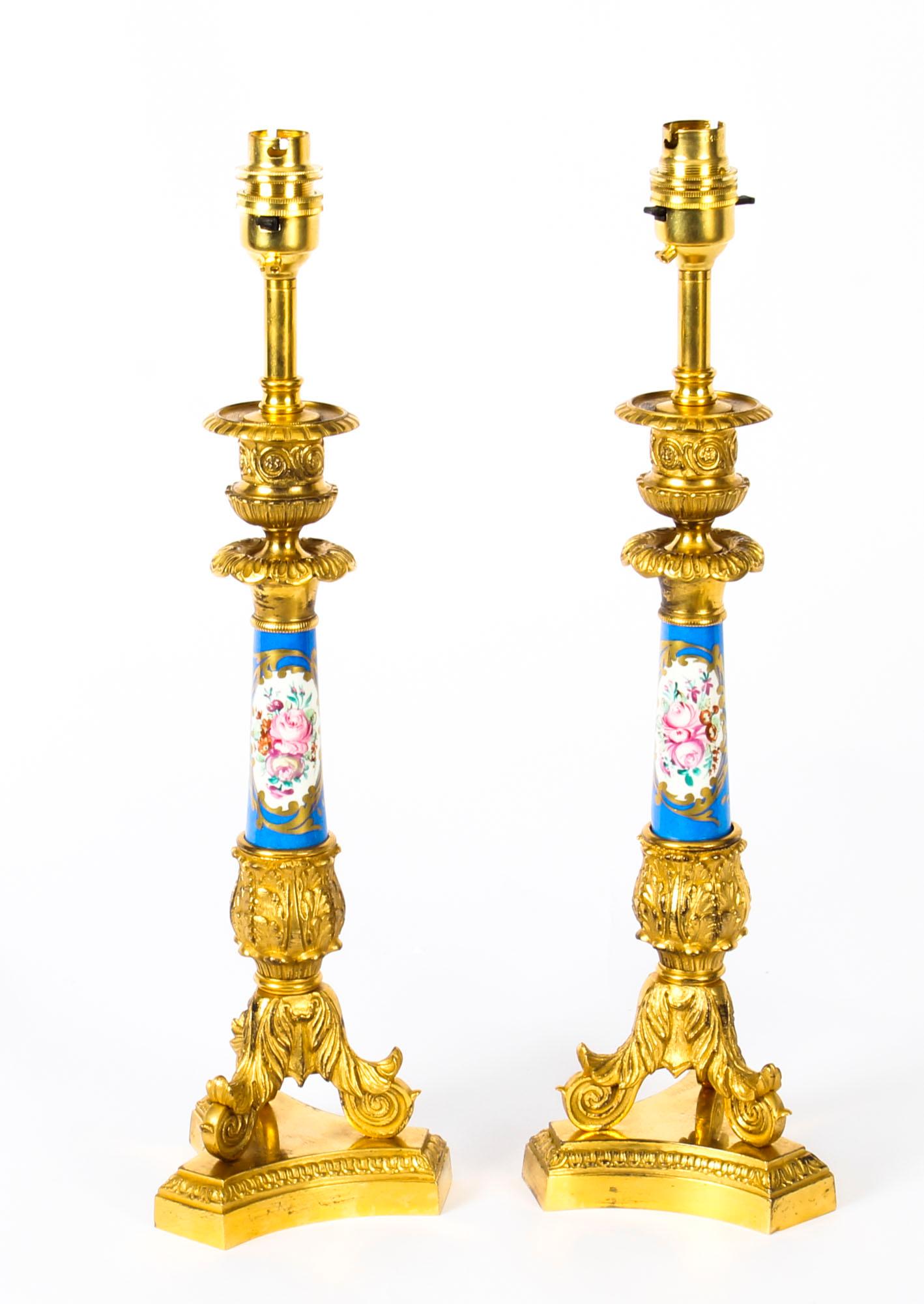 This is a beautiful antique pair of French Sevres Porcelain candlesticks converted to lamps, dating from the late 19th century.

The decorative lamps feature urn form candle sconces above Sèvres porcelain columns decorated with floral reserves on