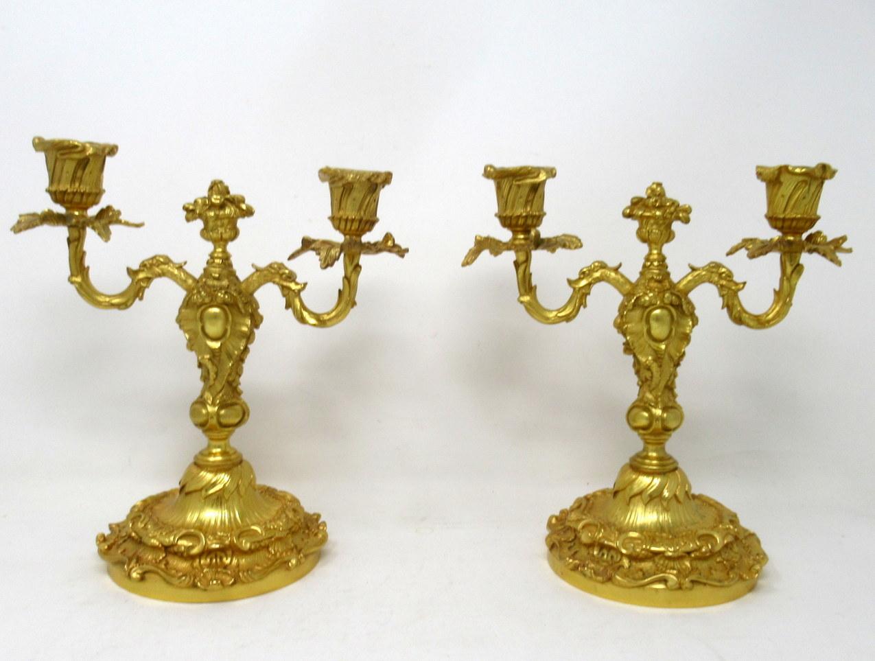 A very stylish pair of twin light chisel cast gilt bronze table or mantel (fireplace) candelabras in George III style, last quarter of the 19th century, of French origin.

Each with central naturalistic finial modelled as an urn filled with fruits