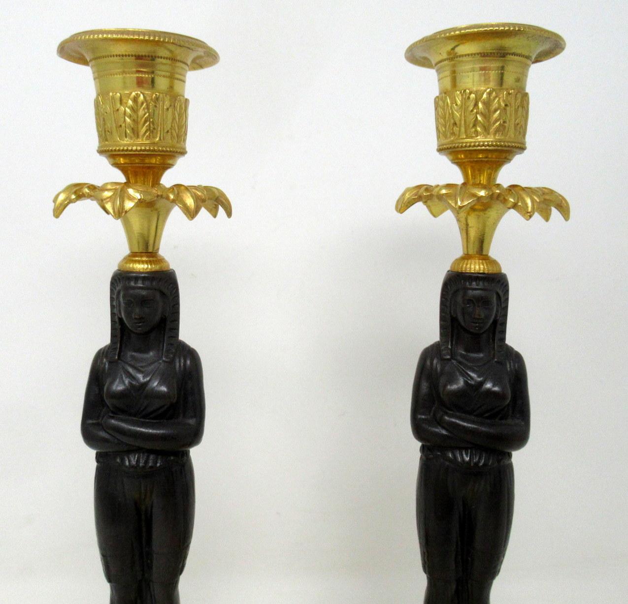 A fine pair of stylish and imposing French ormolu and patinated bronze single light Empire style candlesticks modelled to depict two identical full-length Egyptian female figures in traditional attire of outstanding quality, mid to late 19th