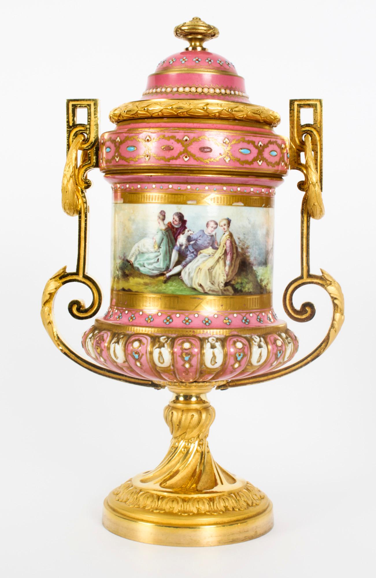 Il s'agit d'une belle paire d'antiquités de vases à couvercle en porcelaine de Sèvres et bronze doré, datant d'environ 1860.
 
Avec leurs couvercles en forme de dôme et leurs corps cannelés, ils sont superbement décorés de scènes de jardin